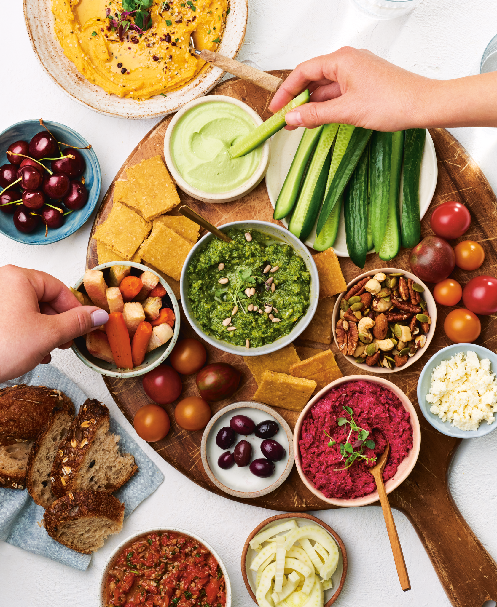 Photography cover of a cookbook titled 'Good Food, Good Mood'  with a variety of colorful dips, fruits, vegetables, and bread on a round wooden serving board for a snack or appetizer platter.