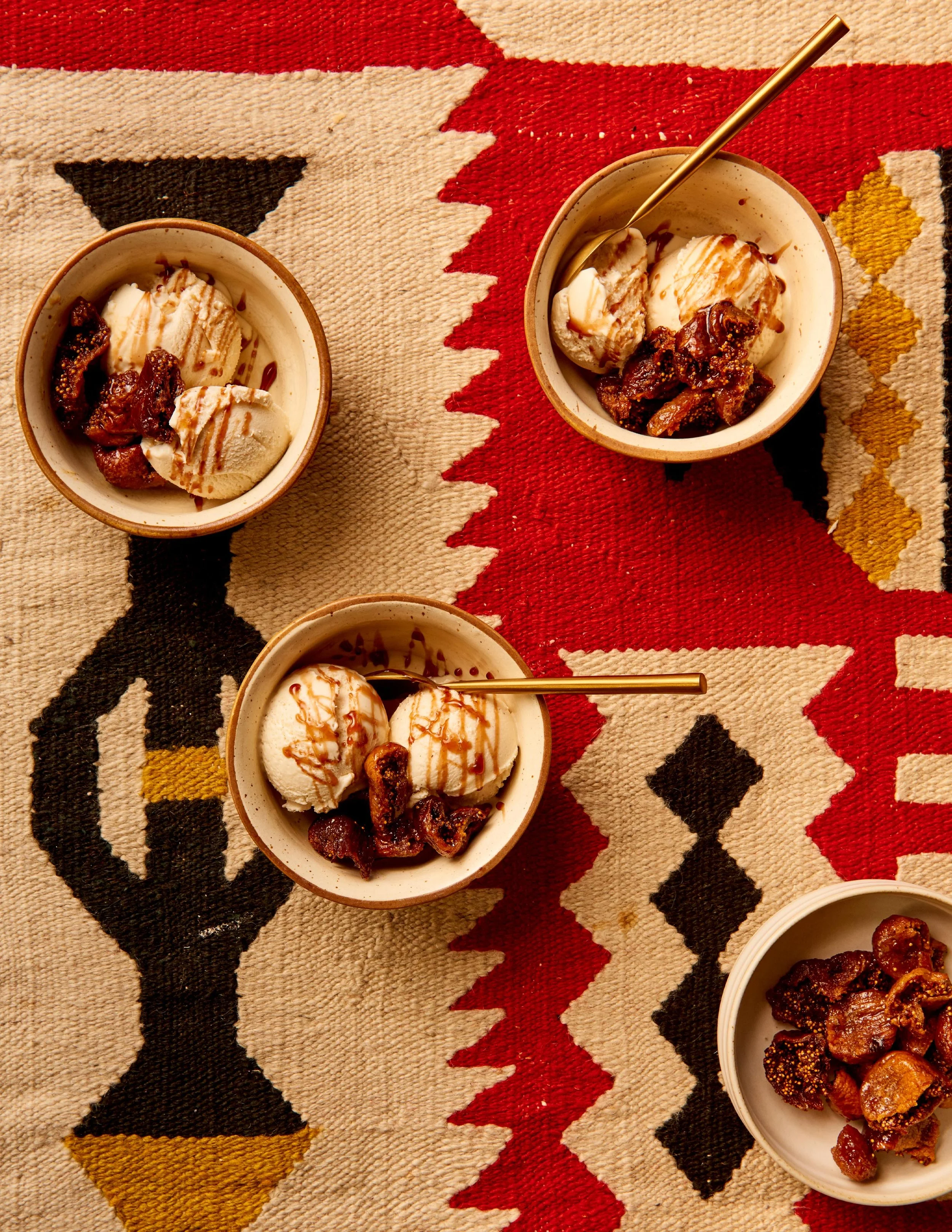 Cover of a cookbook titled "Eat, Habibi, Eat!" by Shahir Massoud. Art directed/styled by rayna marlee. Four bowls of ice cream topped with caramel sauce and bacon pieces on a colorful tribal patterned rug.