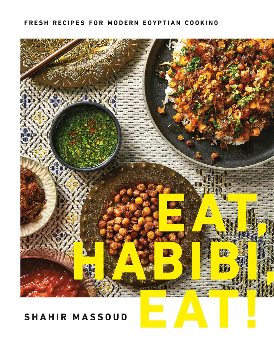 Cover of a cookbook titled "Eat, Habibi, Eat!" by Shahir Massoud. Art directed/styled by rayna marlee. A table setting with traditional Egyptian dishes, including a bowl of chickpeas, a plate of rice with vegetables, and various sauces and garnishes.