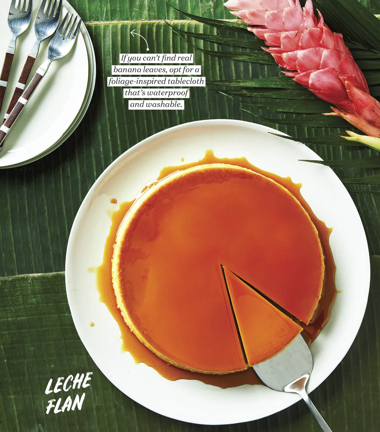 Chatelaine Magazine, styled by rayna marA caramel flan on a white plate with a slice removed, set on a background of large tropical leaves with a pink ginger blossom. A small fork and additional plates with utensils are visible in the top left corner