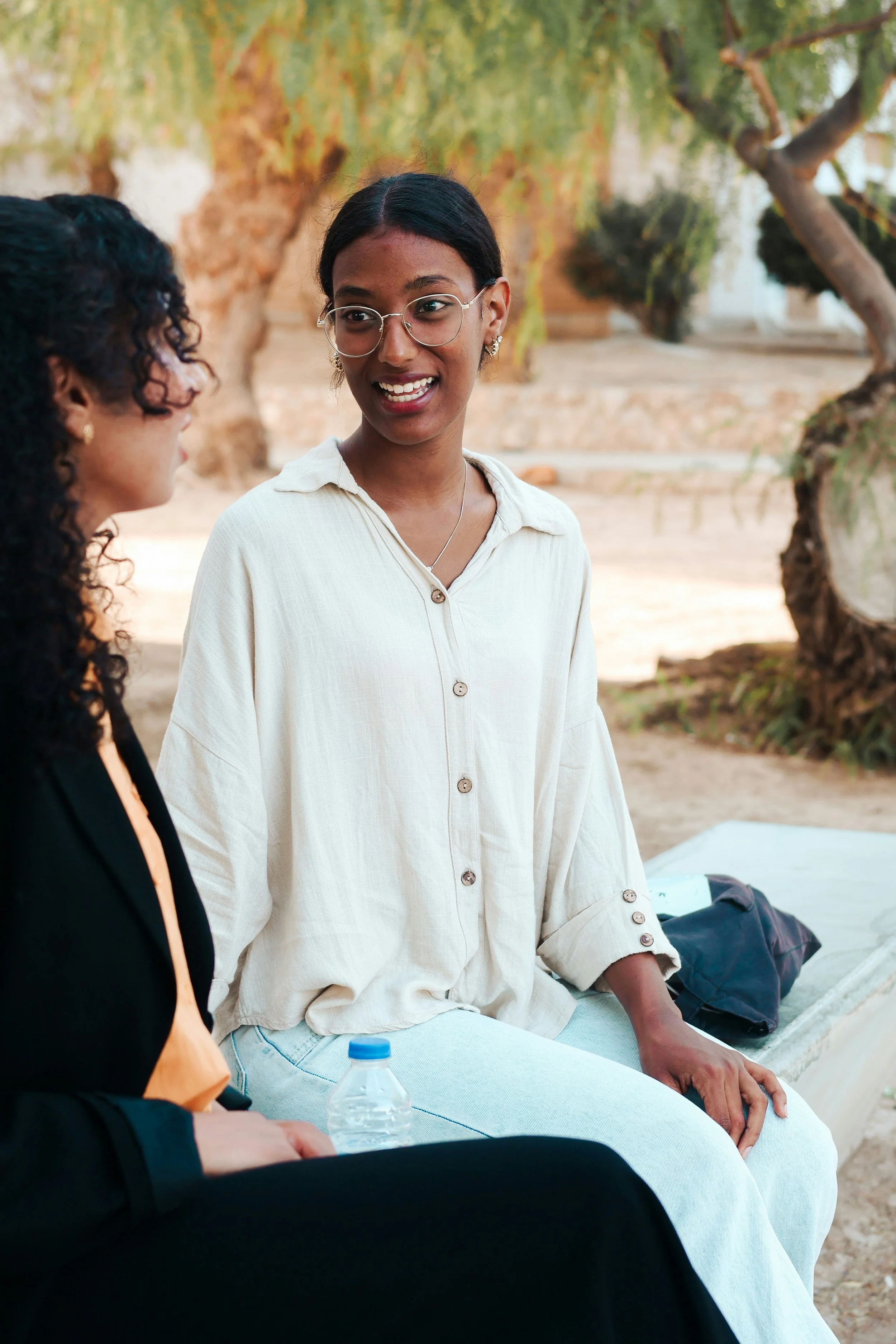 Two women talking while sitting on a bench outdoors.