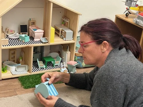 Sarah Everett playing with a dollhouse during a play therapy session