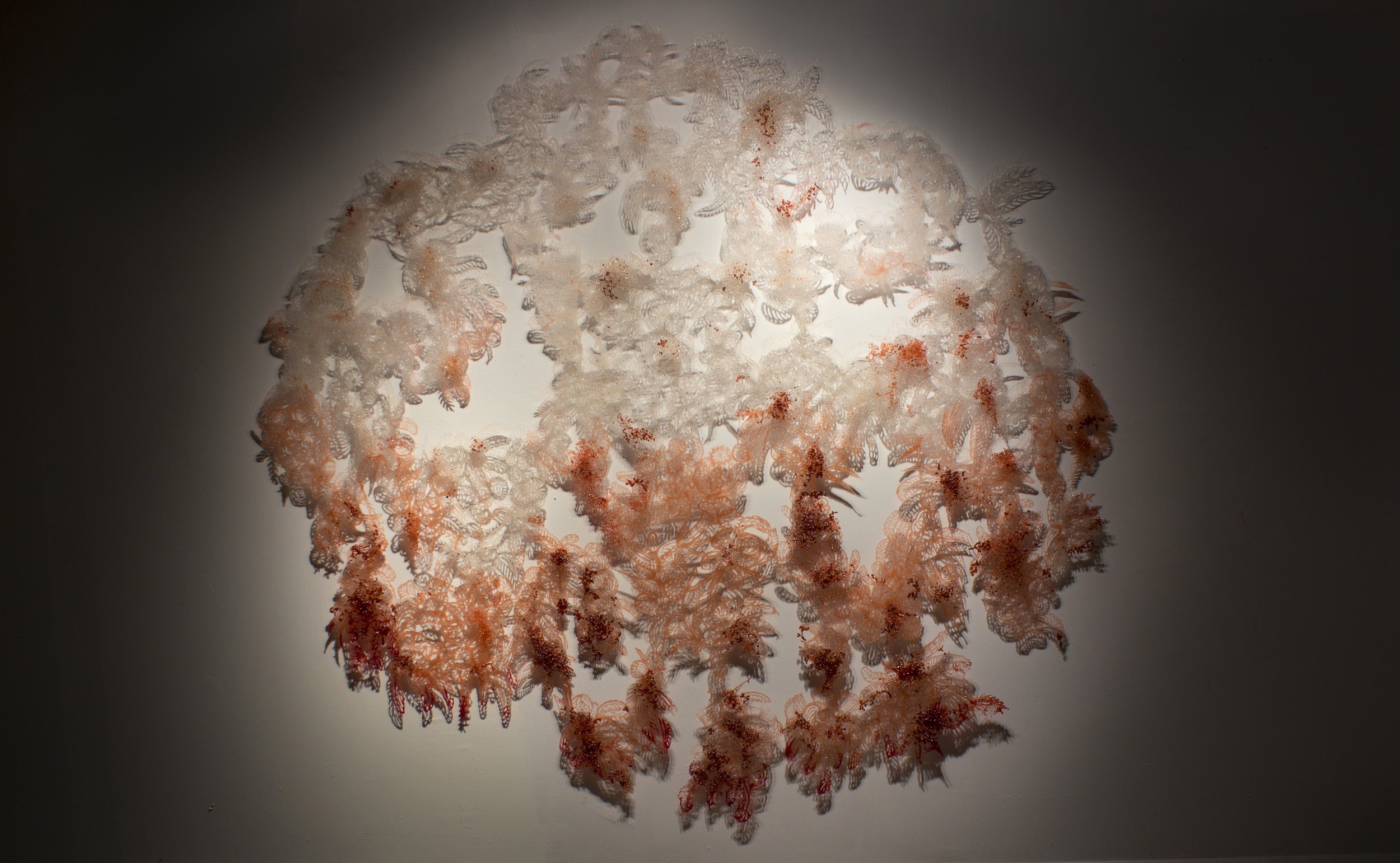 Image of entire sculpture made of delicate pink floral shapes made of glass.
