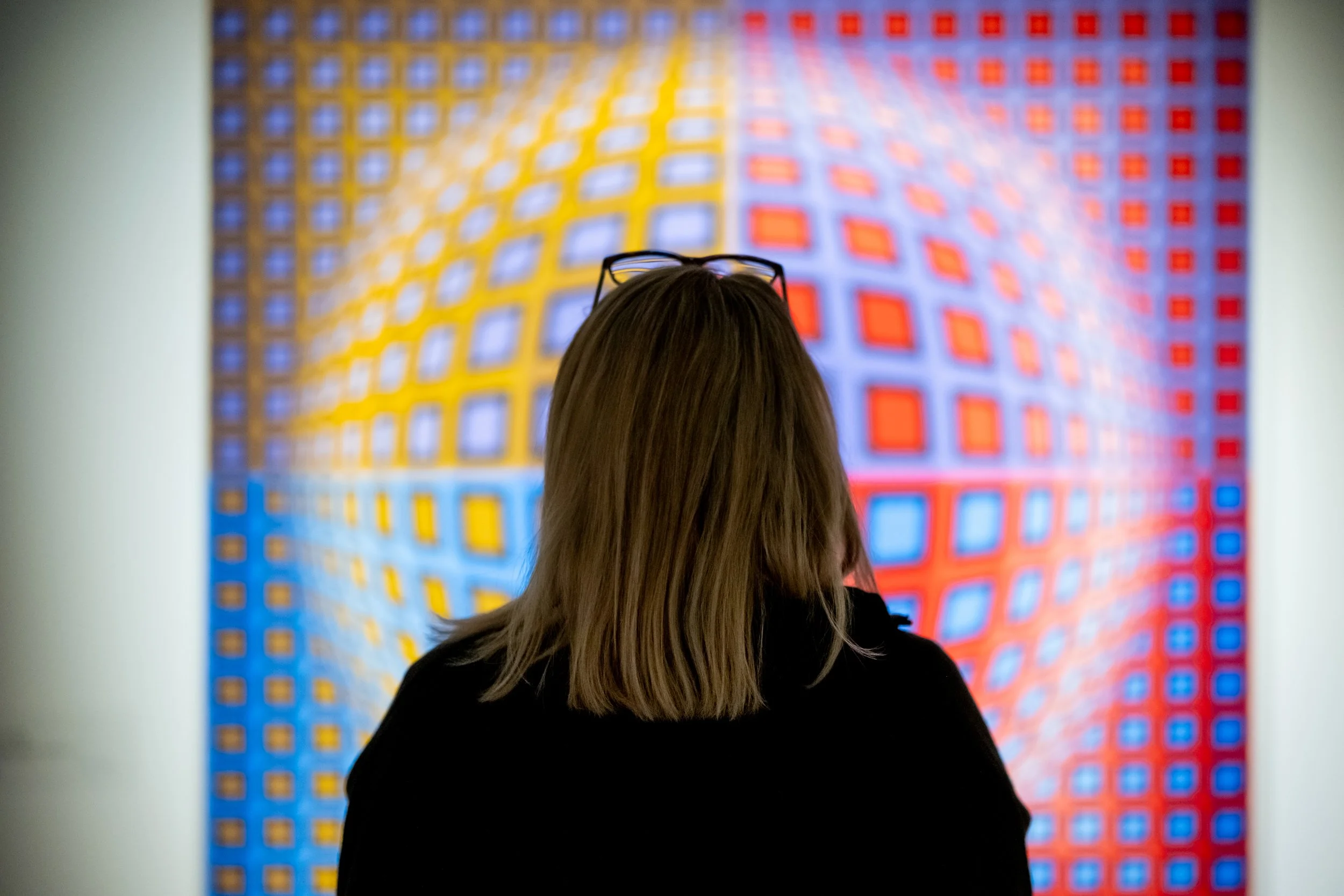 A woman looking at an optical illusion painting by artist Victor Vasarely. 