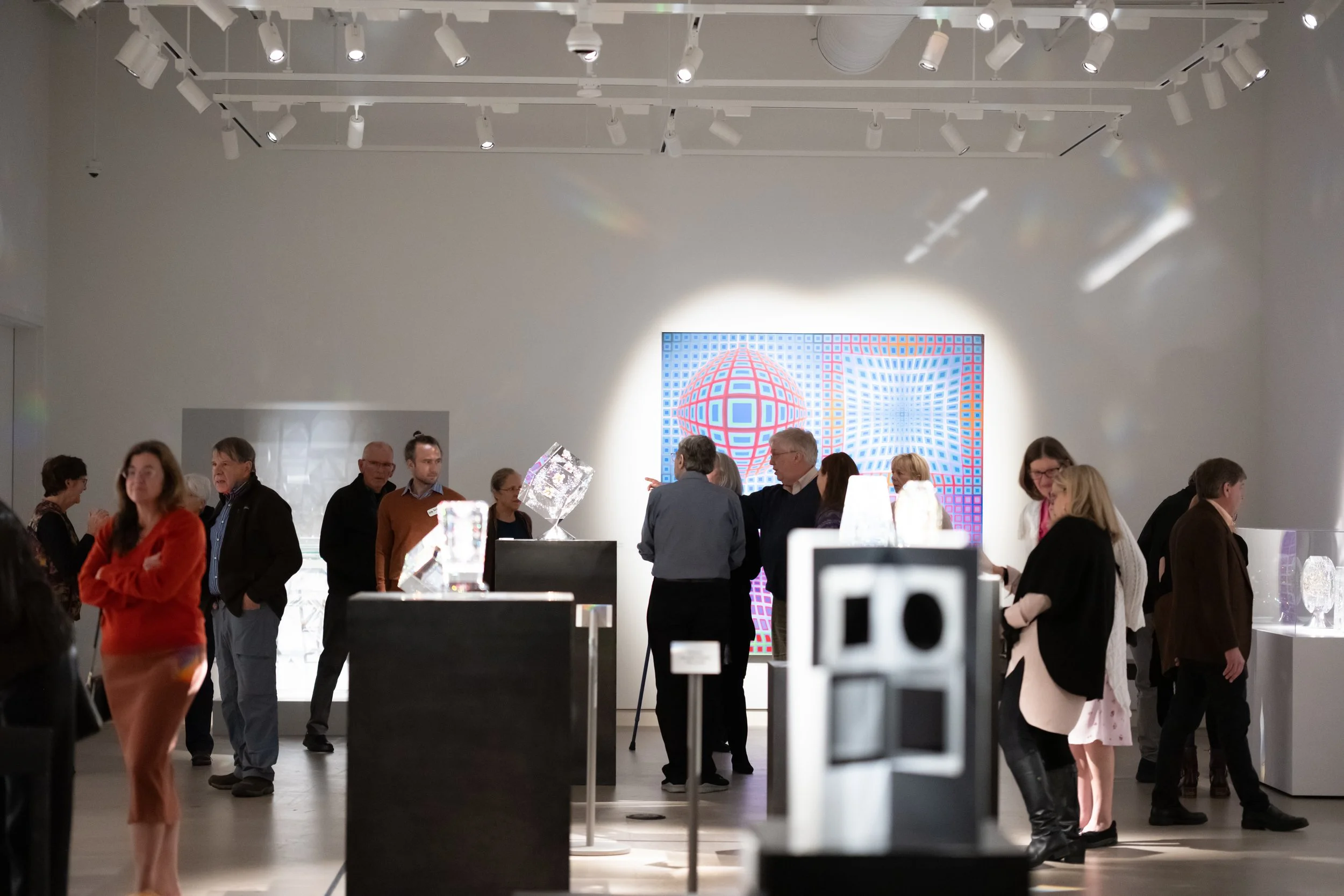 People gathered in a gallery, looking at various artworks. 