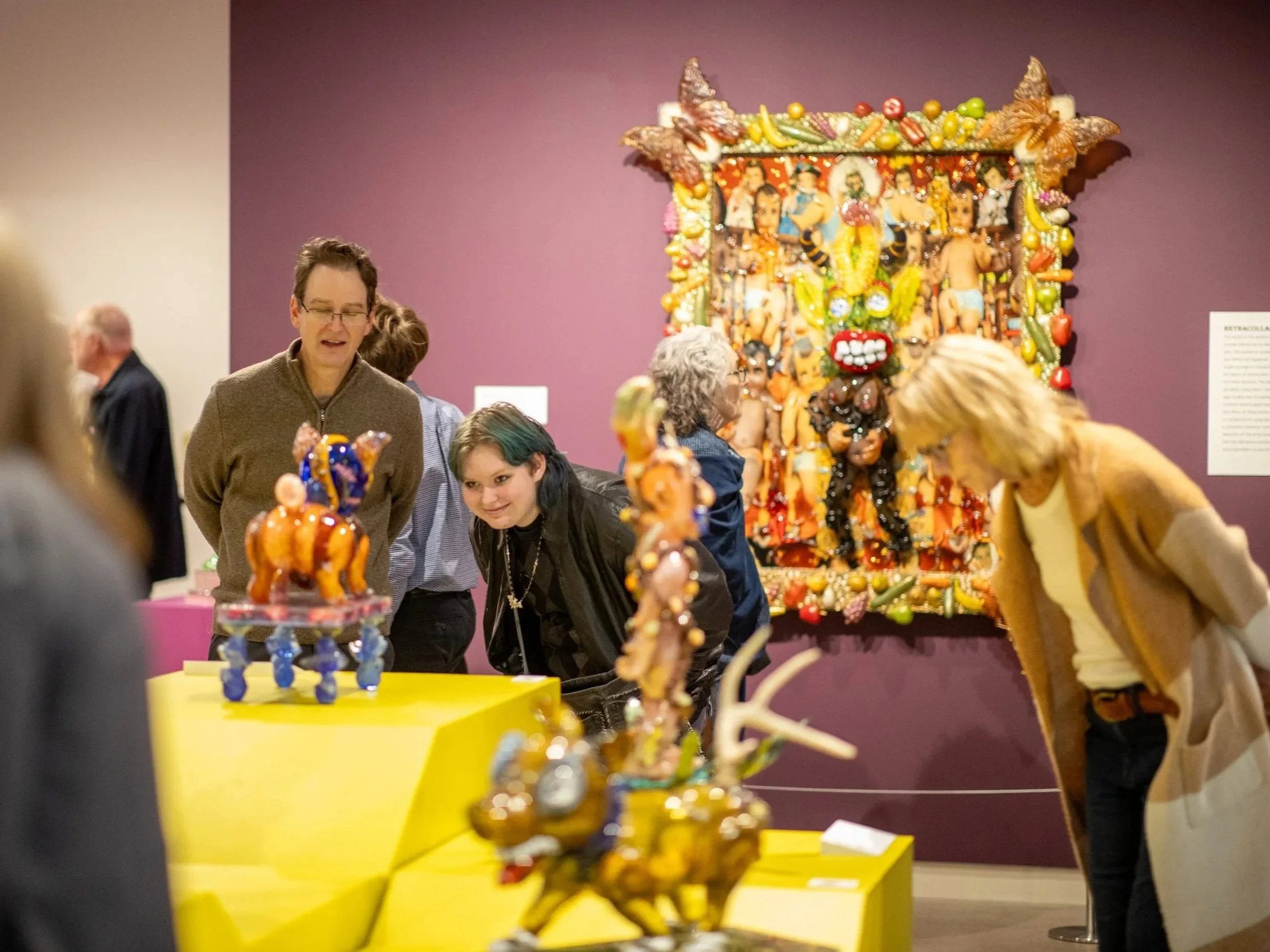 People viewing vibrant and colorful art installations in a museum setting.