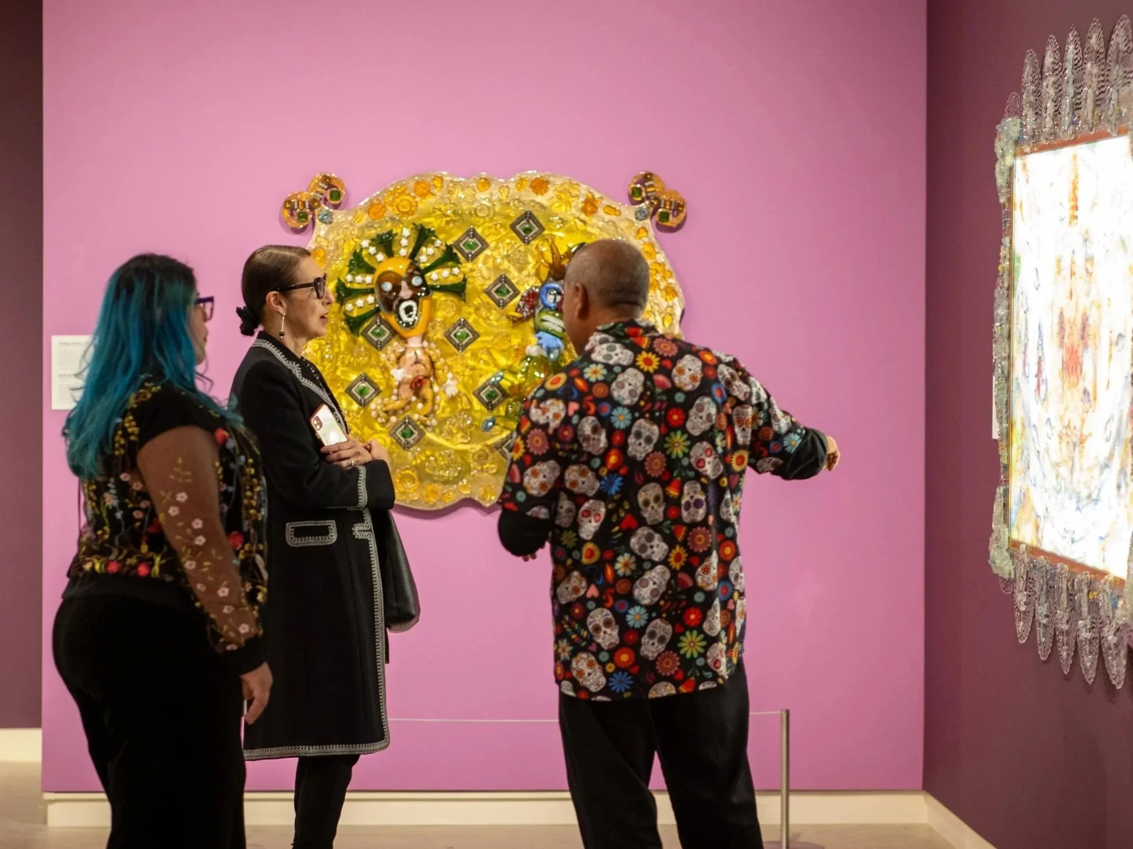 Three adults discuss an artwork in the gallery.