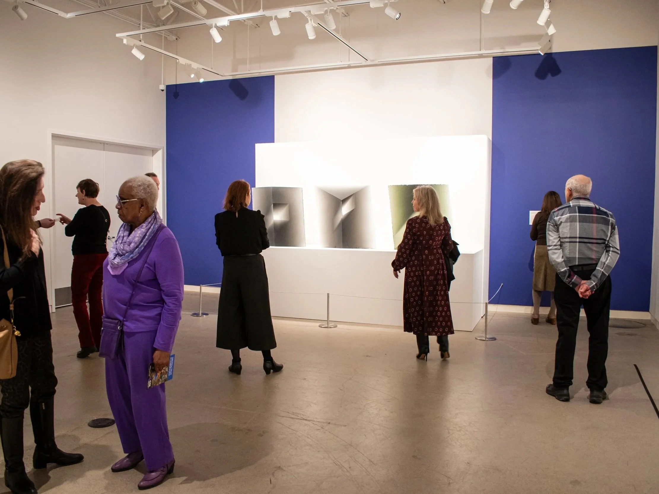 Various visitors looking at work throughout a gallery.