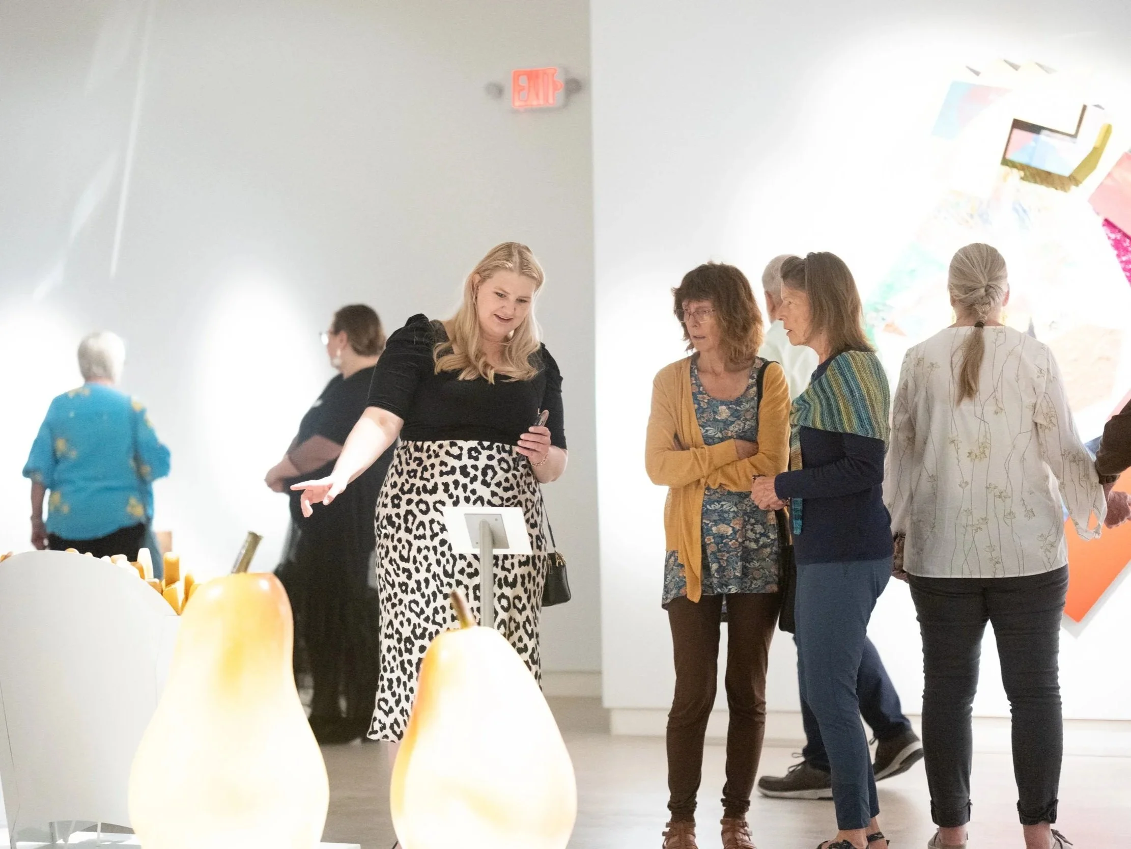 Women discussing large sculptures in a gallery.