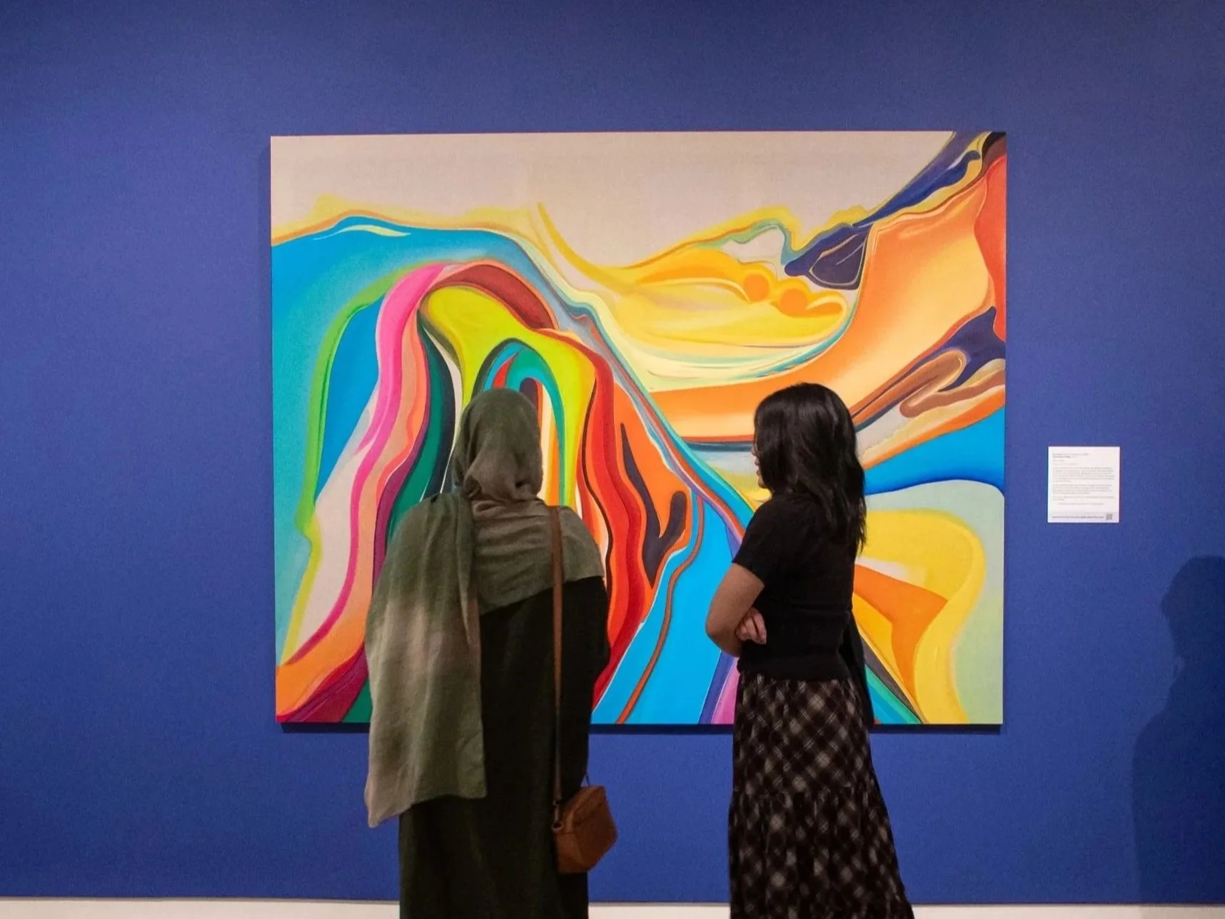 Two teenagers looking at a colorful abstract painting.
