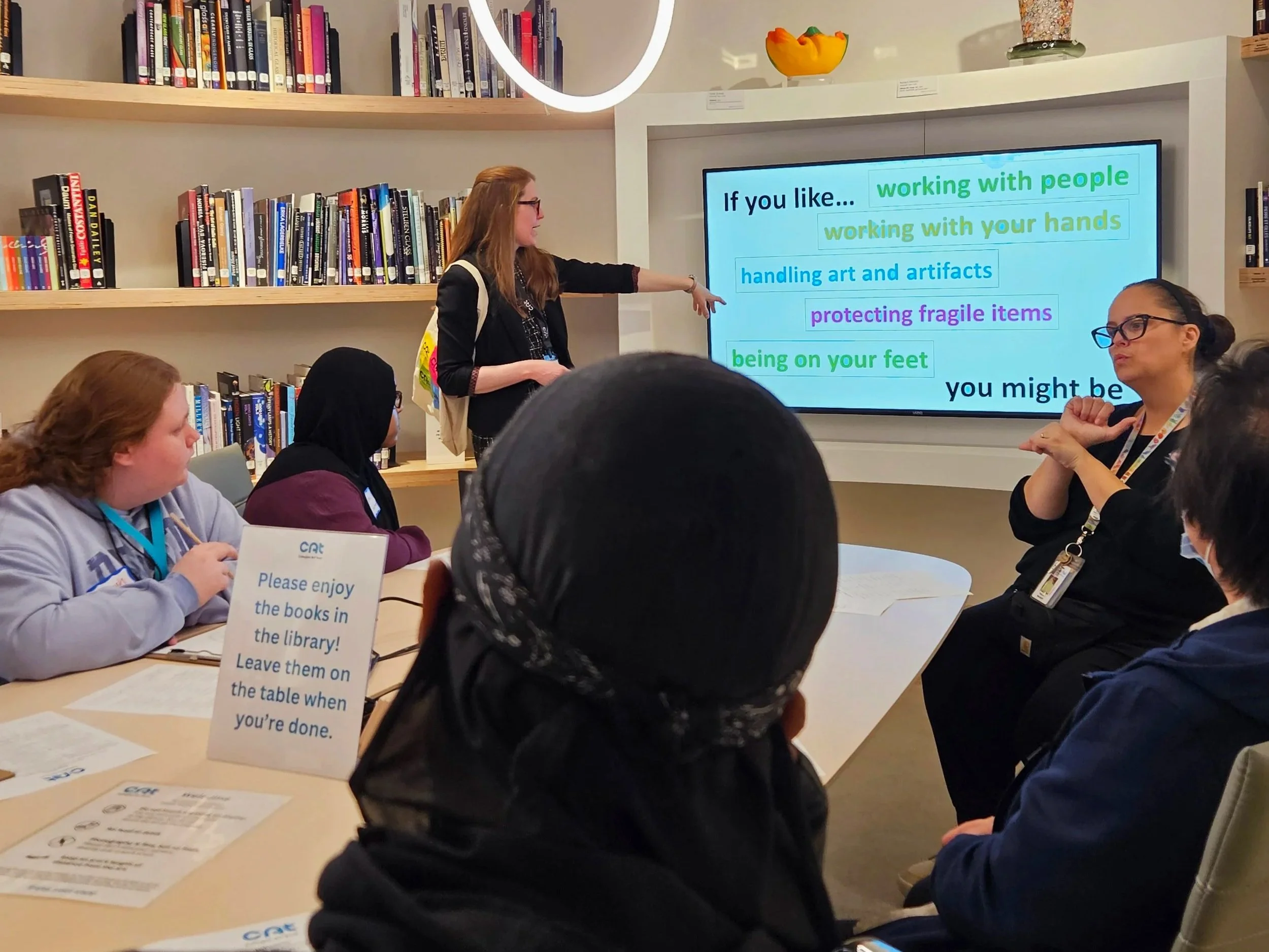 Students participating in a museum careers talk led by a museum educator, with an ASL interpreter seated in the front.