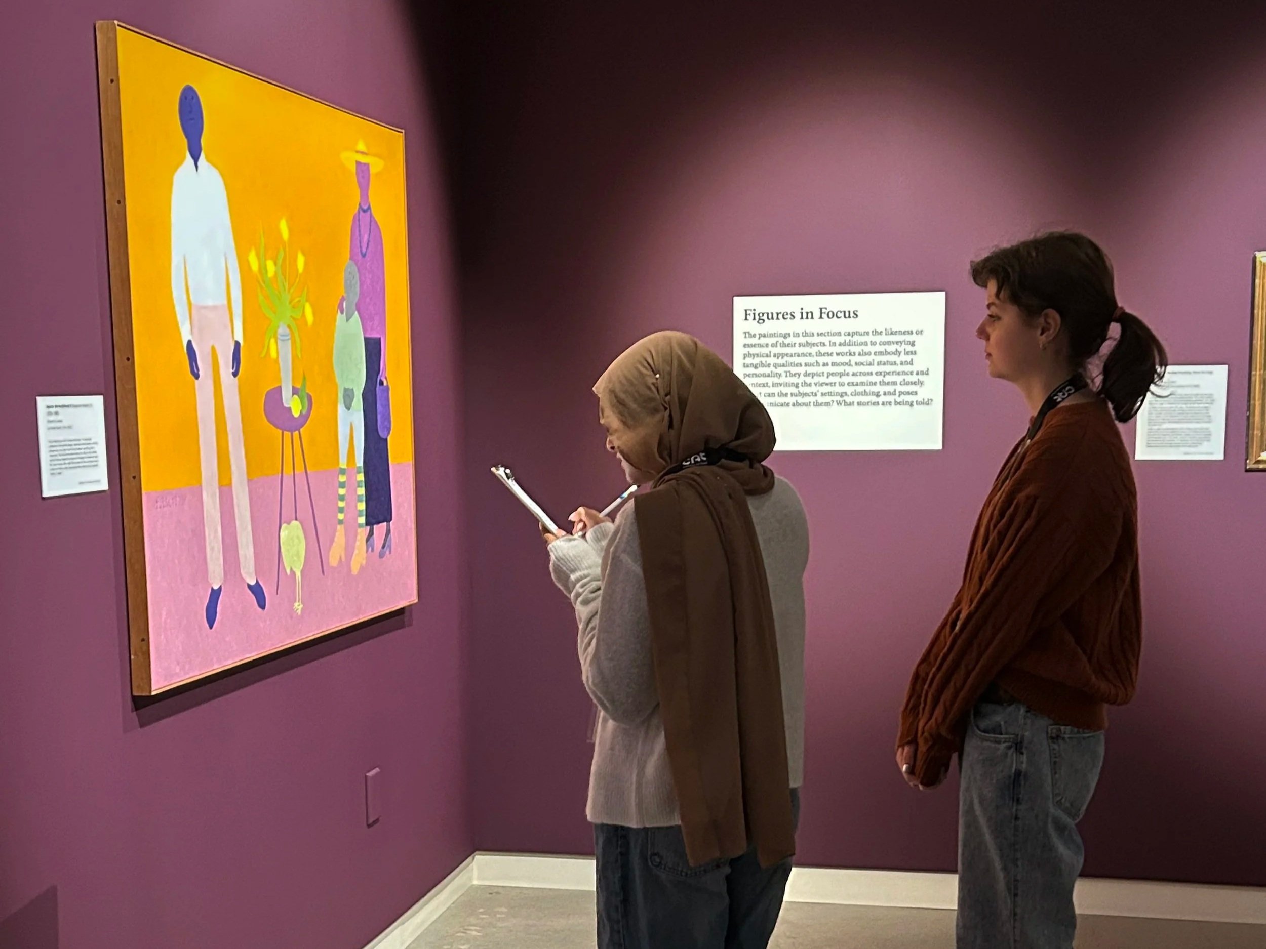 Two teenagers study a painting in the gallery.