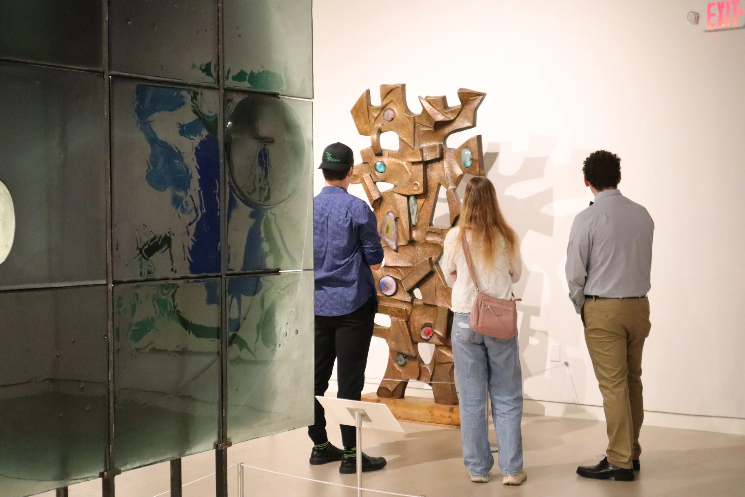  Three teenagers look at a sculpture in a gallery. 