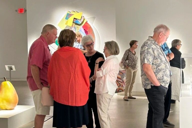 A group of people look at art and converse in the gallery. 