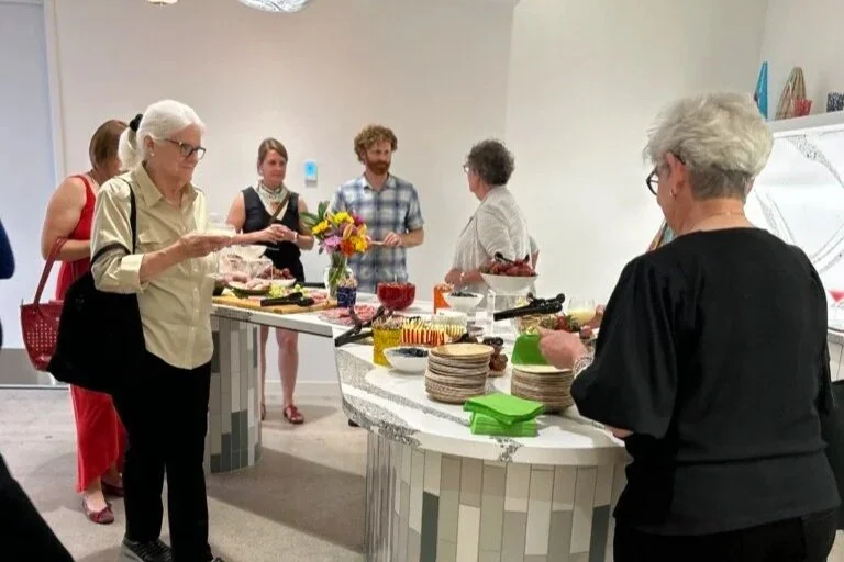 People serve themselves food from a spread on a counter. 