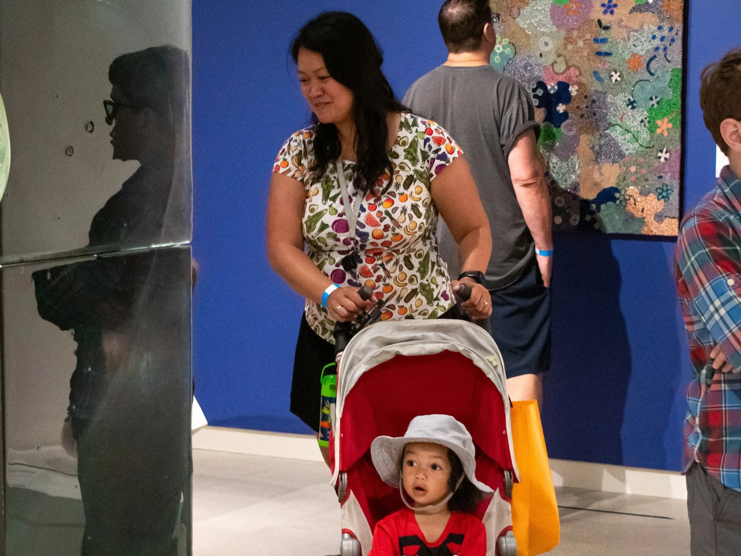 An adult woman and children in a stroller look at a large glass sculpture. 
