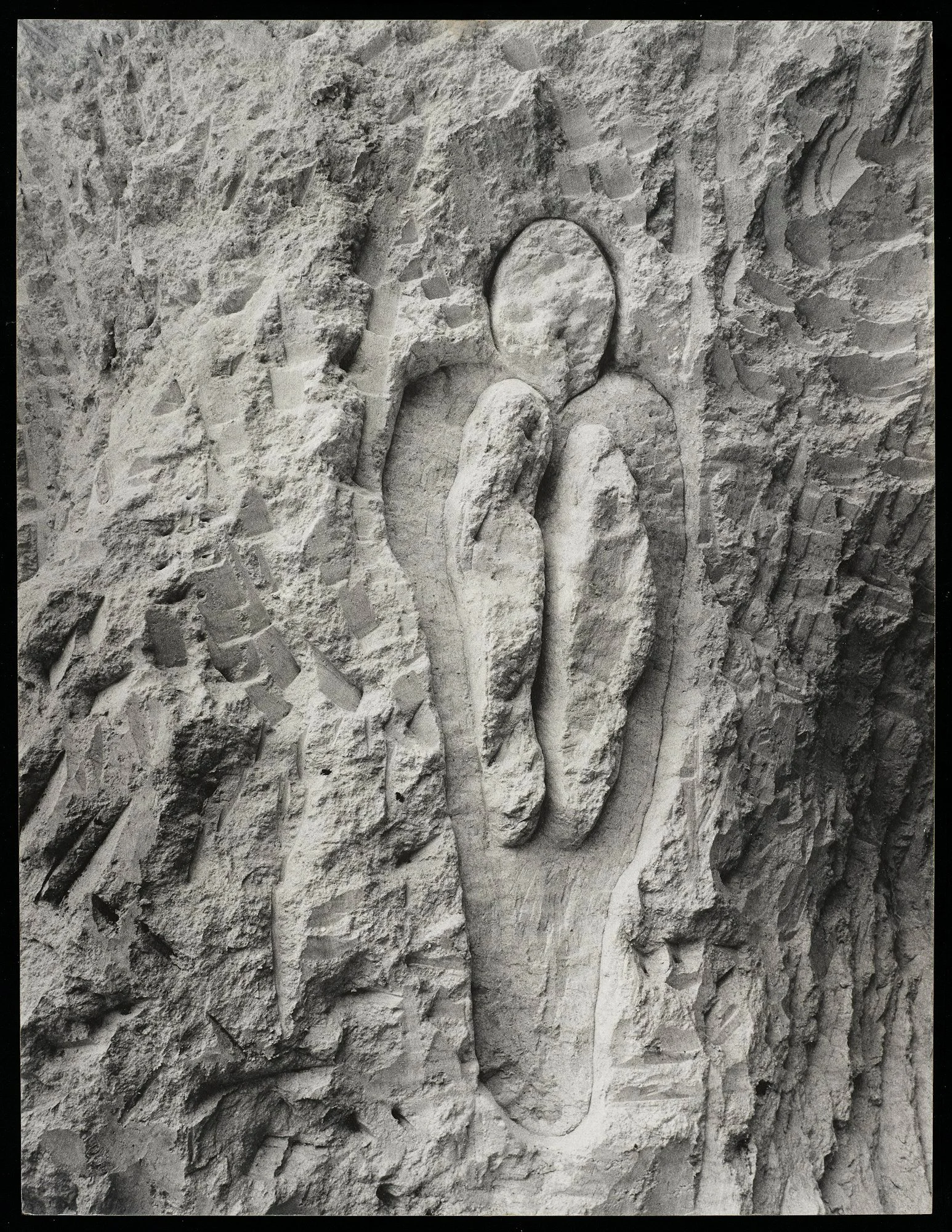 Photograph of human figure carved into stone, inside the figure are two smaller oblong shapes.