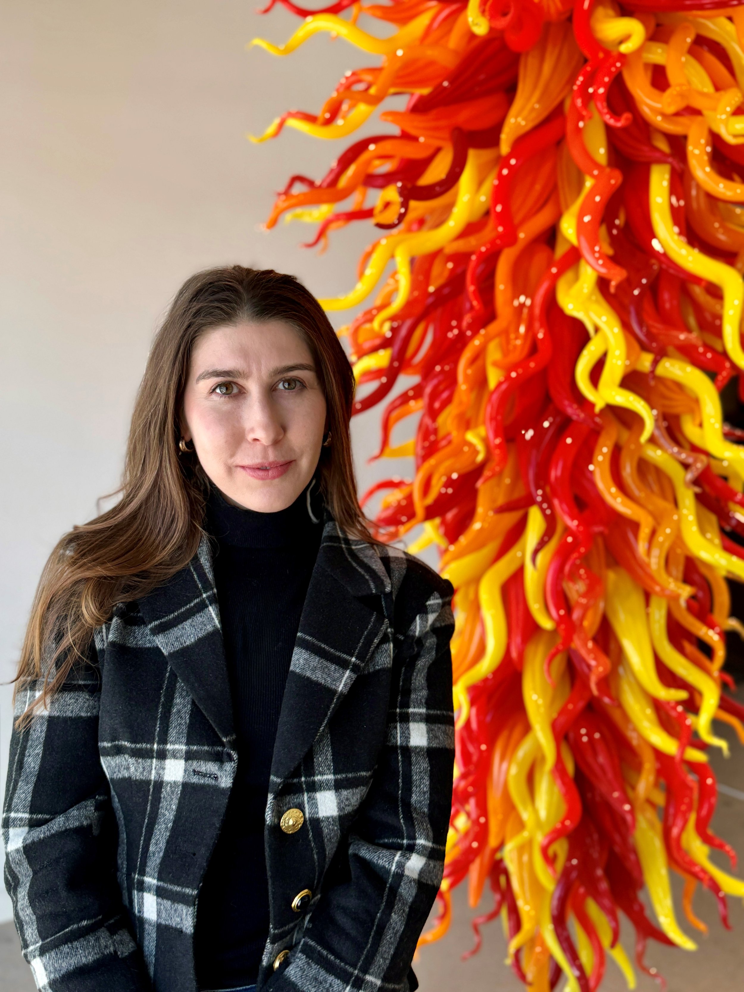 A headshot of Jennifer Rappaport with a Chihuly sculpture behind her.