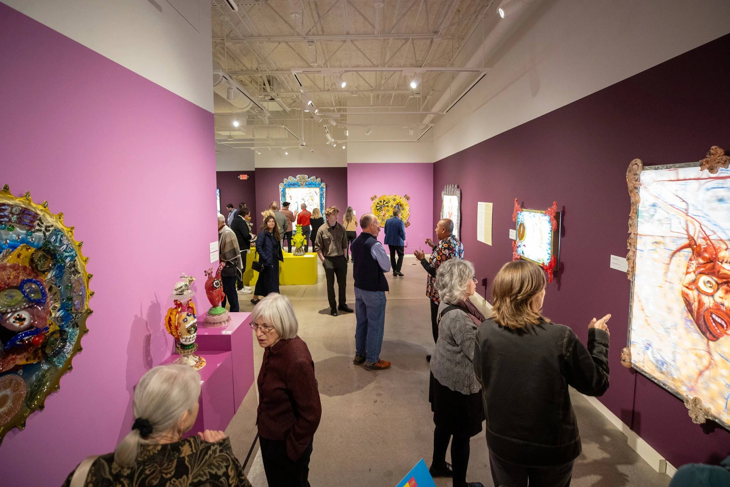 Guests at an opening celebration studying the exhibition.