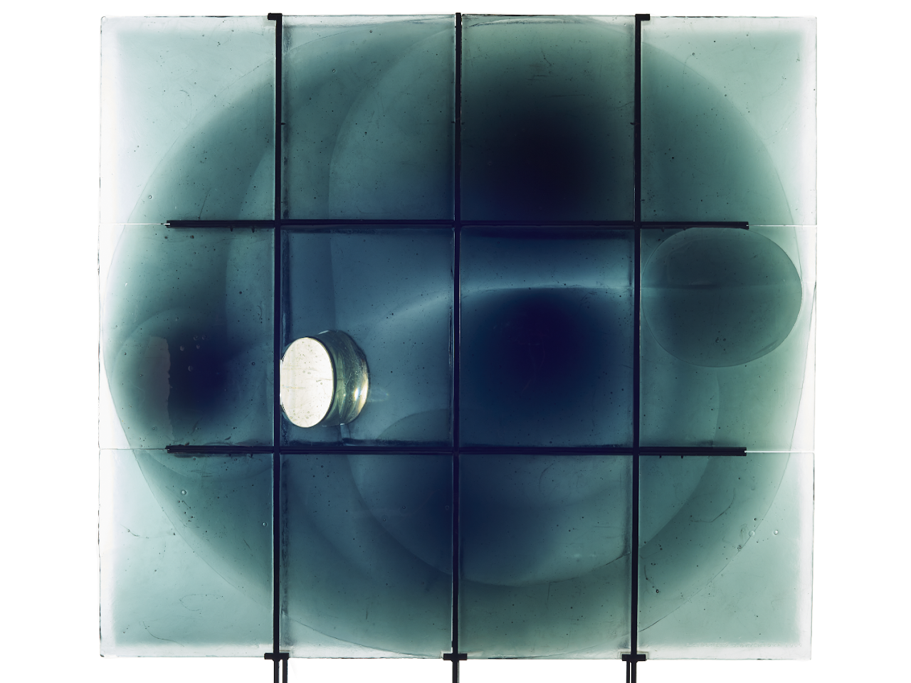 A glass ceiling with a grid pattern, showing multiple circular reflections and shadows from sunlight.