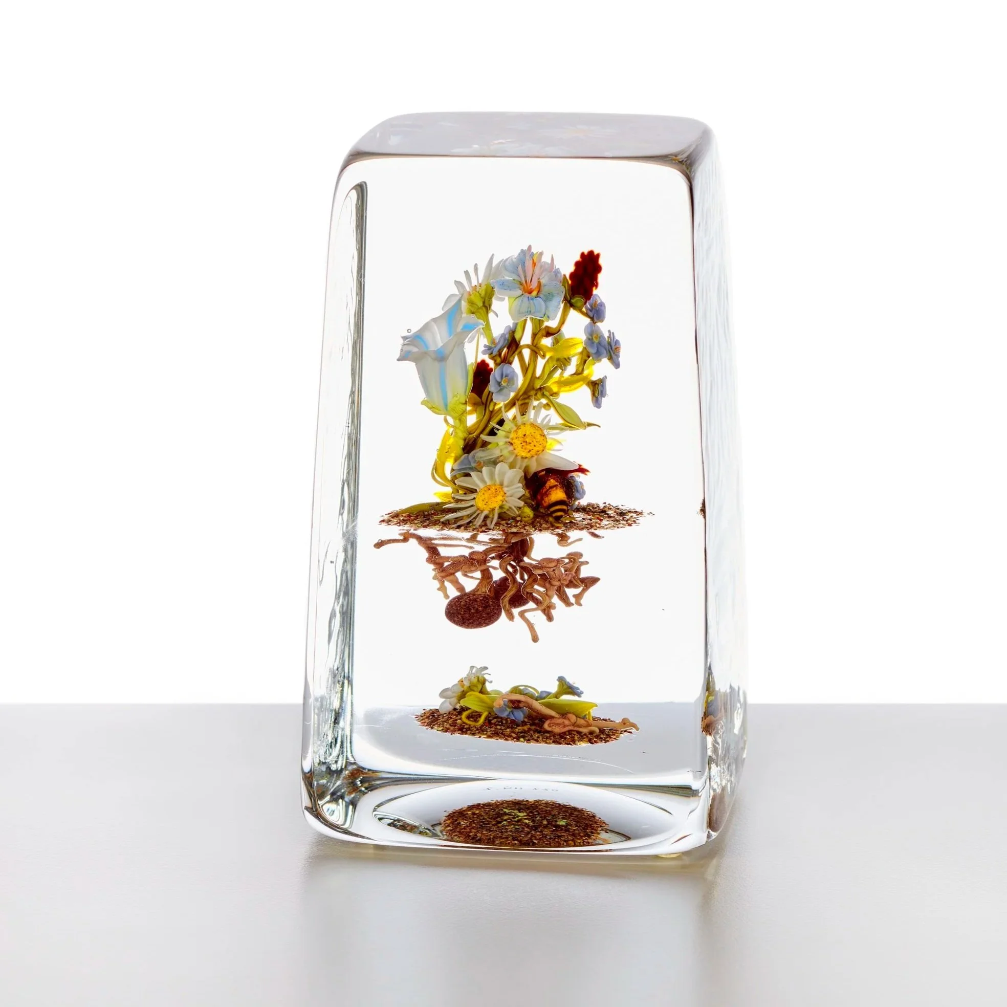 A rectangular glass paperweight with florals and insects inside.