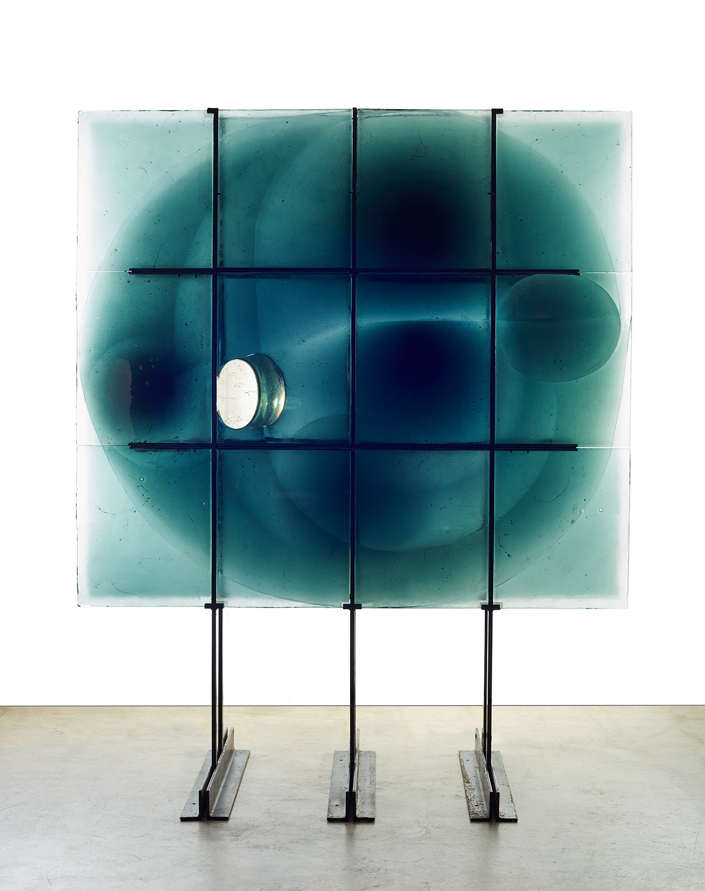 Large abstract glass sculpture made of green-blue squares set into a metal grid.