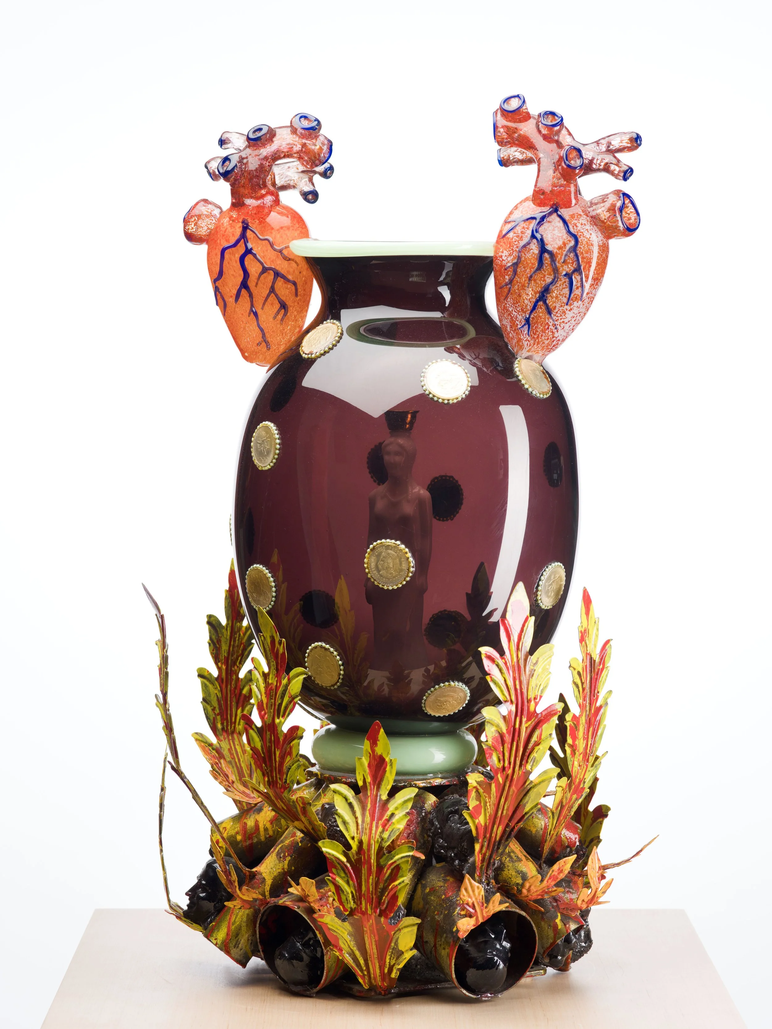 A mixed-media sculpture of a large glass vessel with decoration on top and bottom.