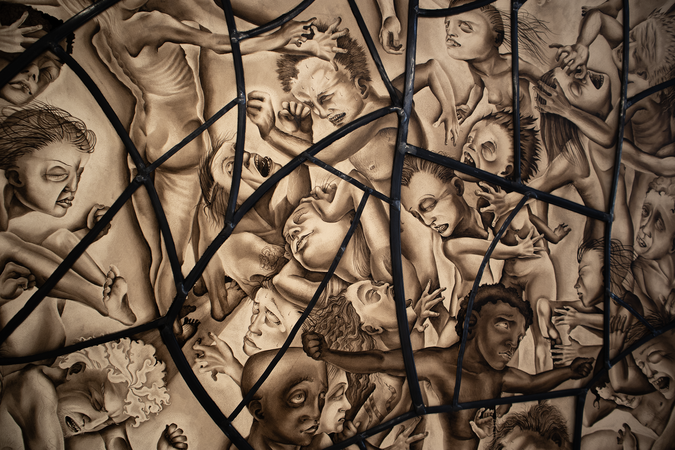 A mural of agitated, distressed human faces and figures, surrounded by black metal fence bars.
