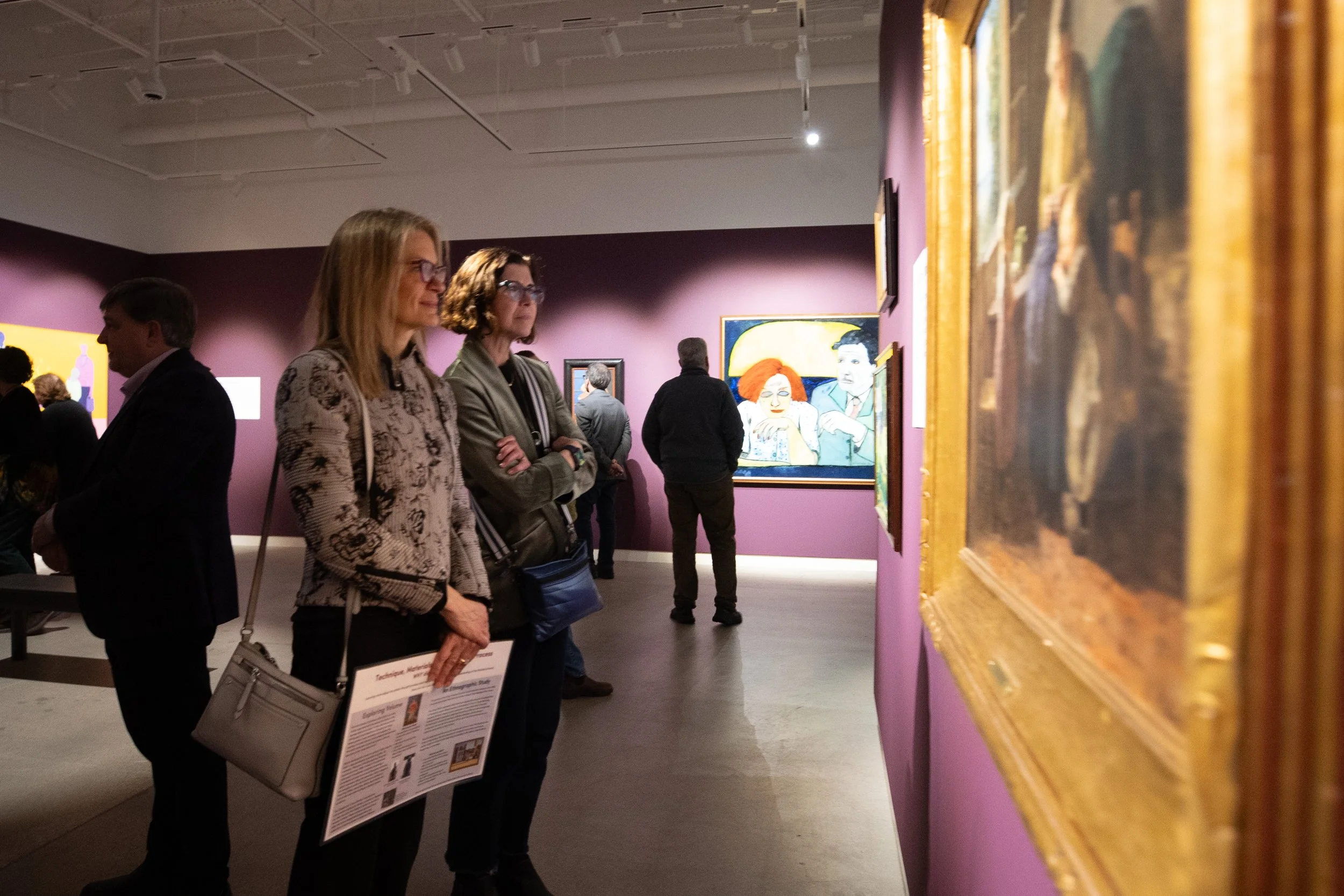 People look at paintings in the gallery. 