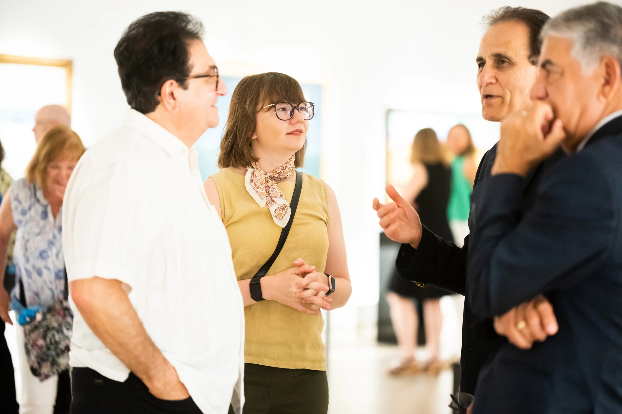 A group of adults converse in a gallery.