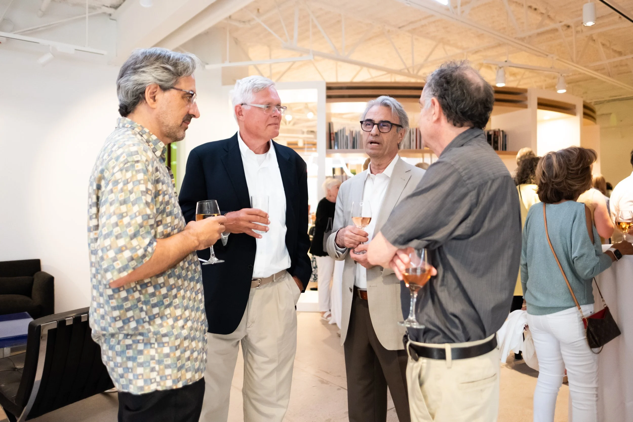 A group of adults gather and converse while holding drinks. 
