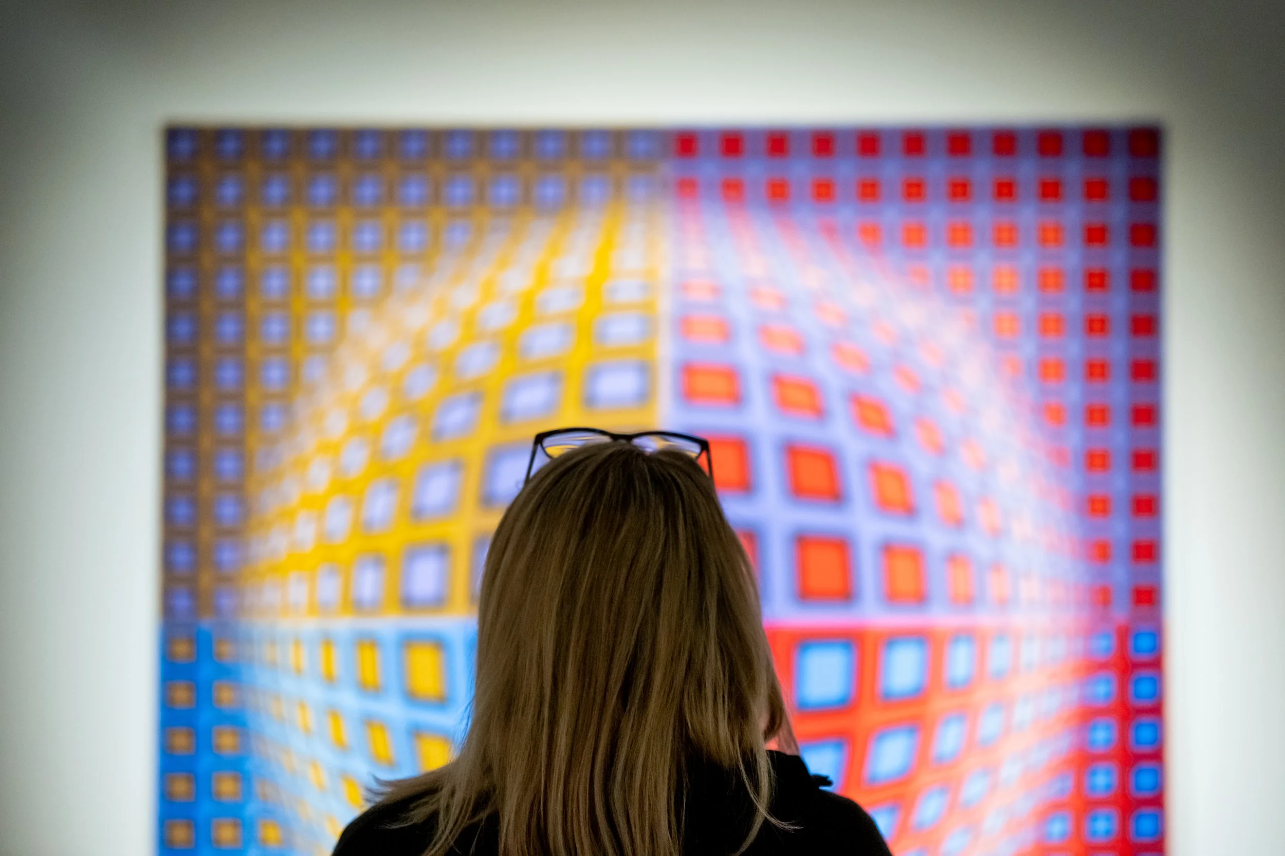 The back of a person's head centered in front of an artwork on the wall. 