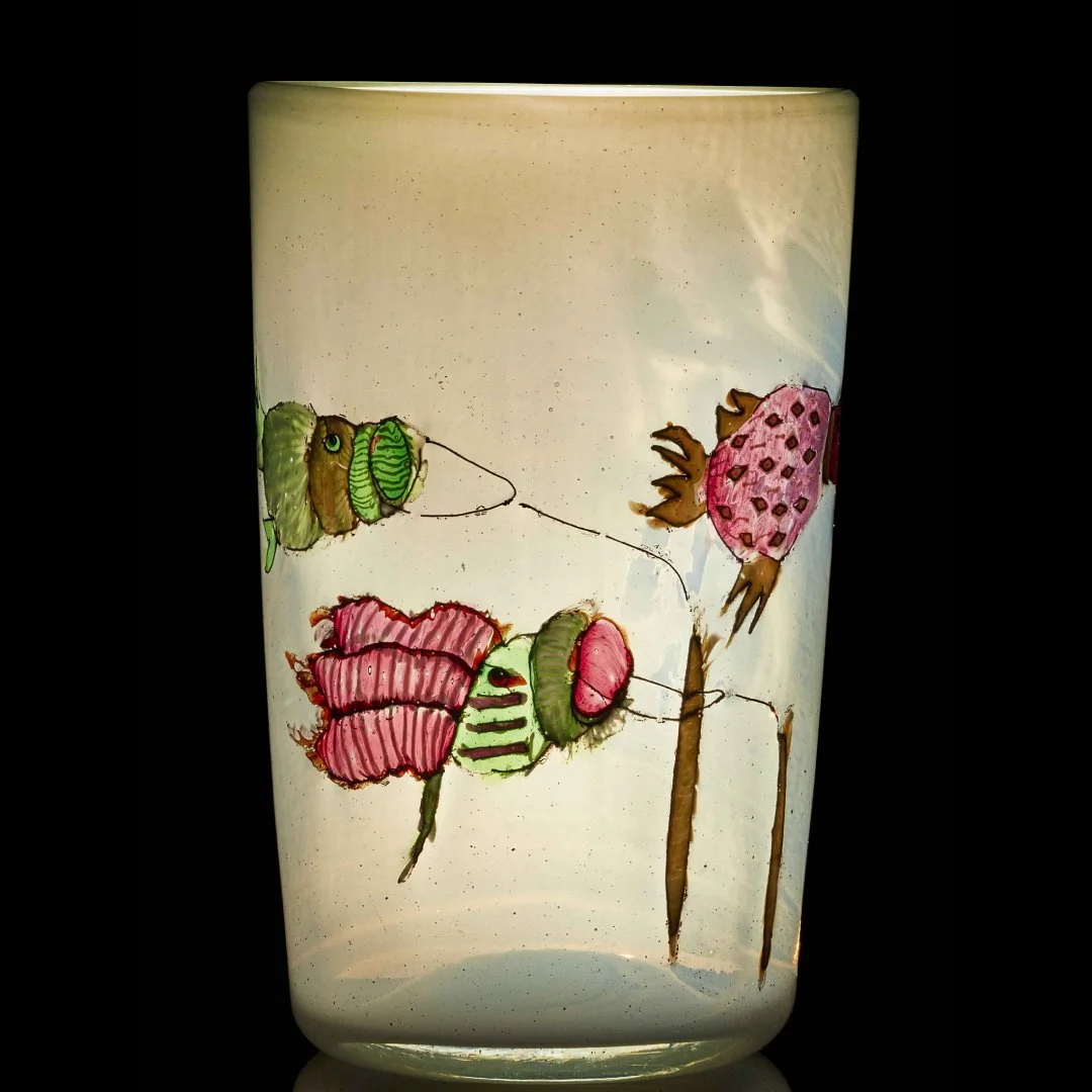 A slightly opaque cylindrical vase with pink and green illustrsation.
