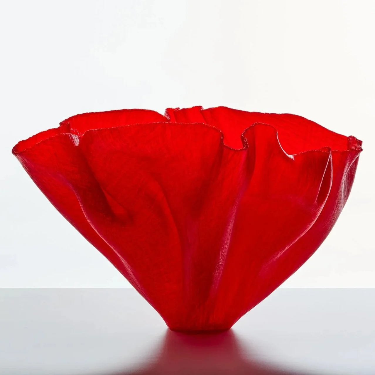 Red glass sculptural vase with folds.