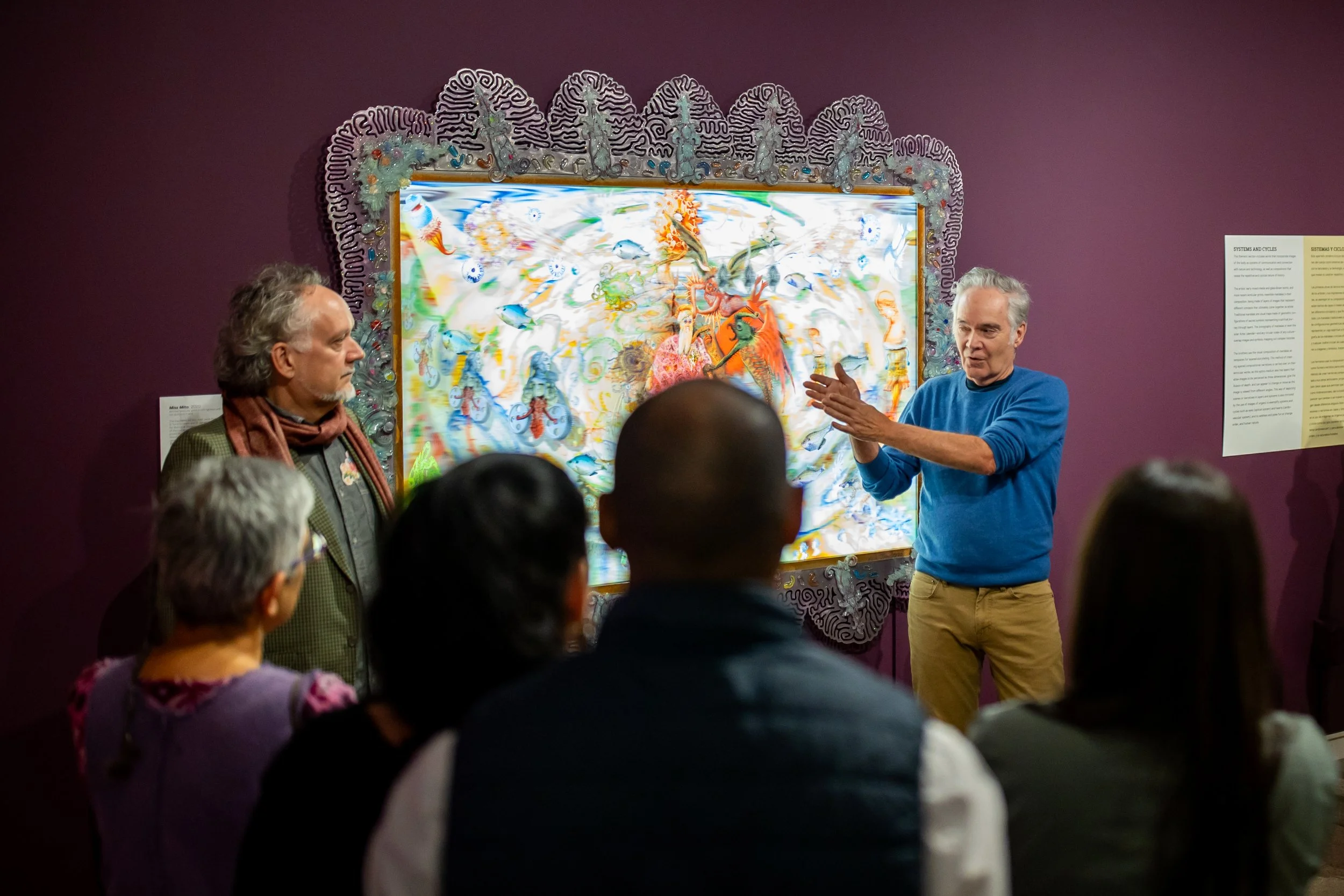 The de la Torre brothers speaking together in front of one of their artworks.