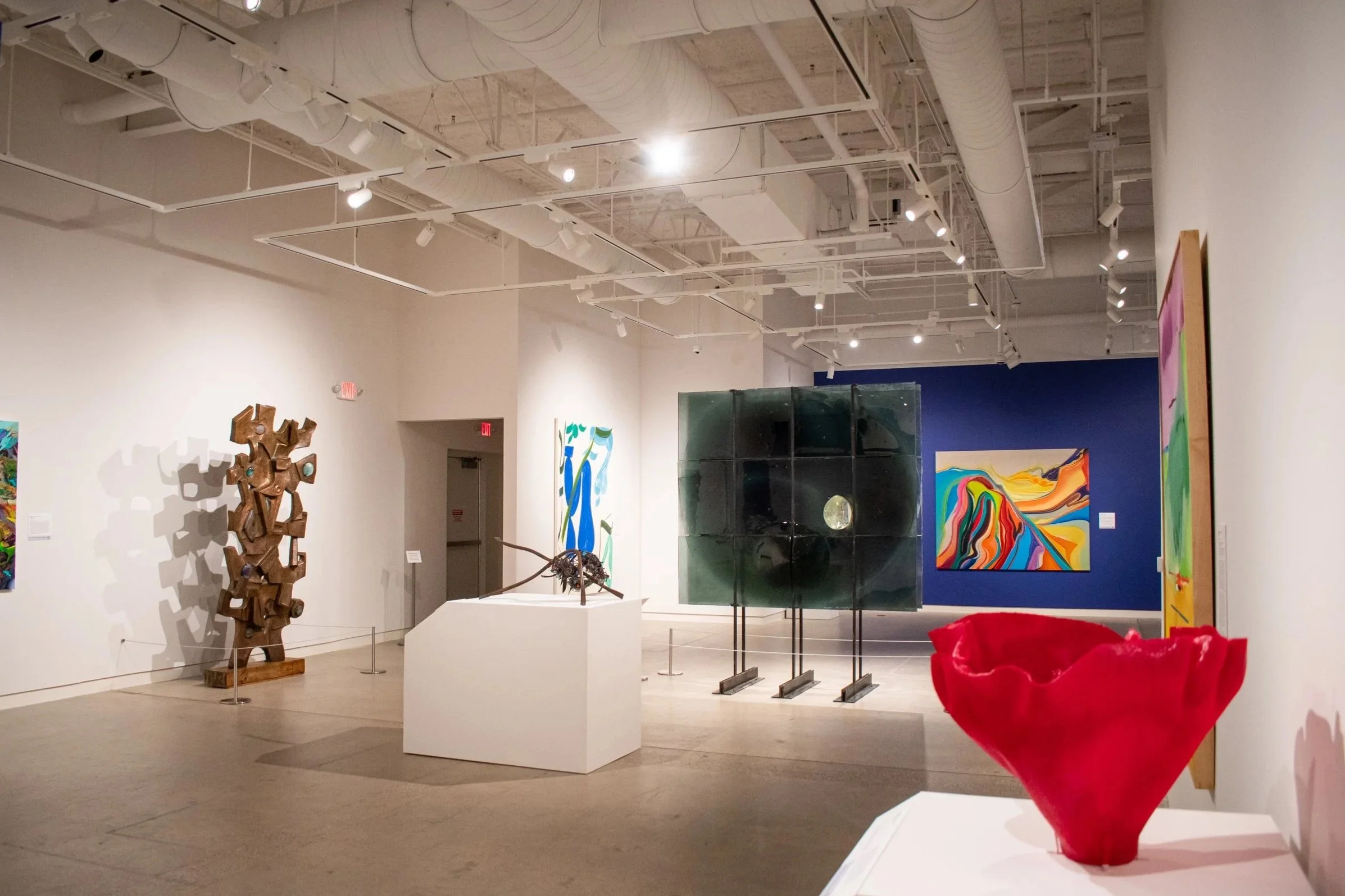 Large abstract sculptures and colorful paintings in an exhibition gallery.