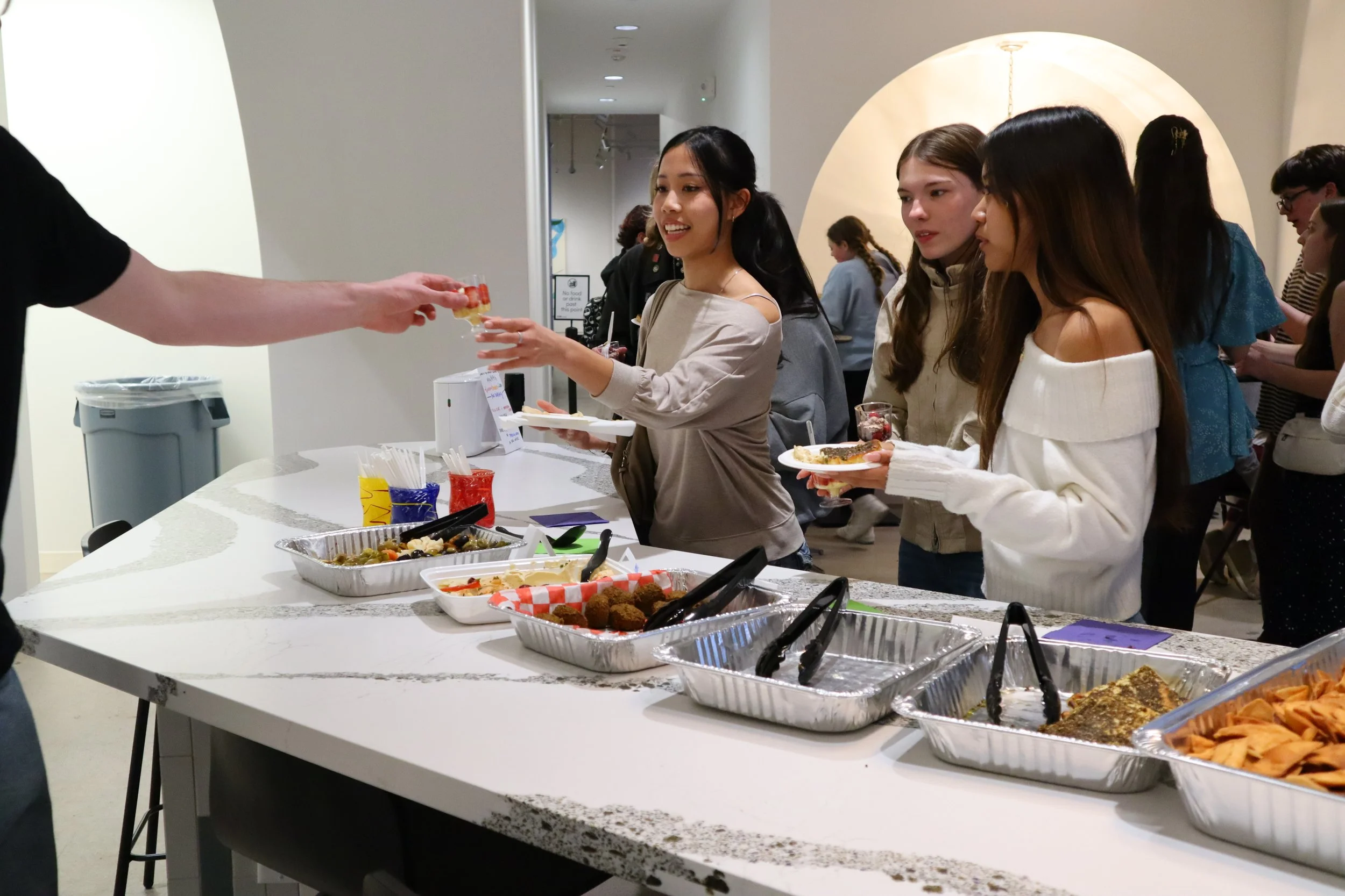 Teenagers receiving food and drink, standing along a high counter top.