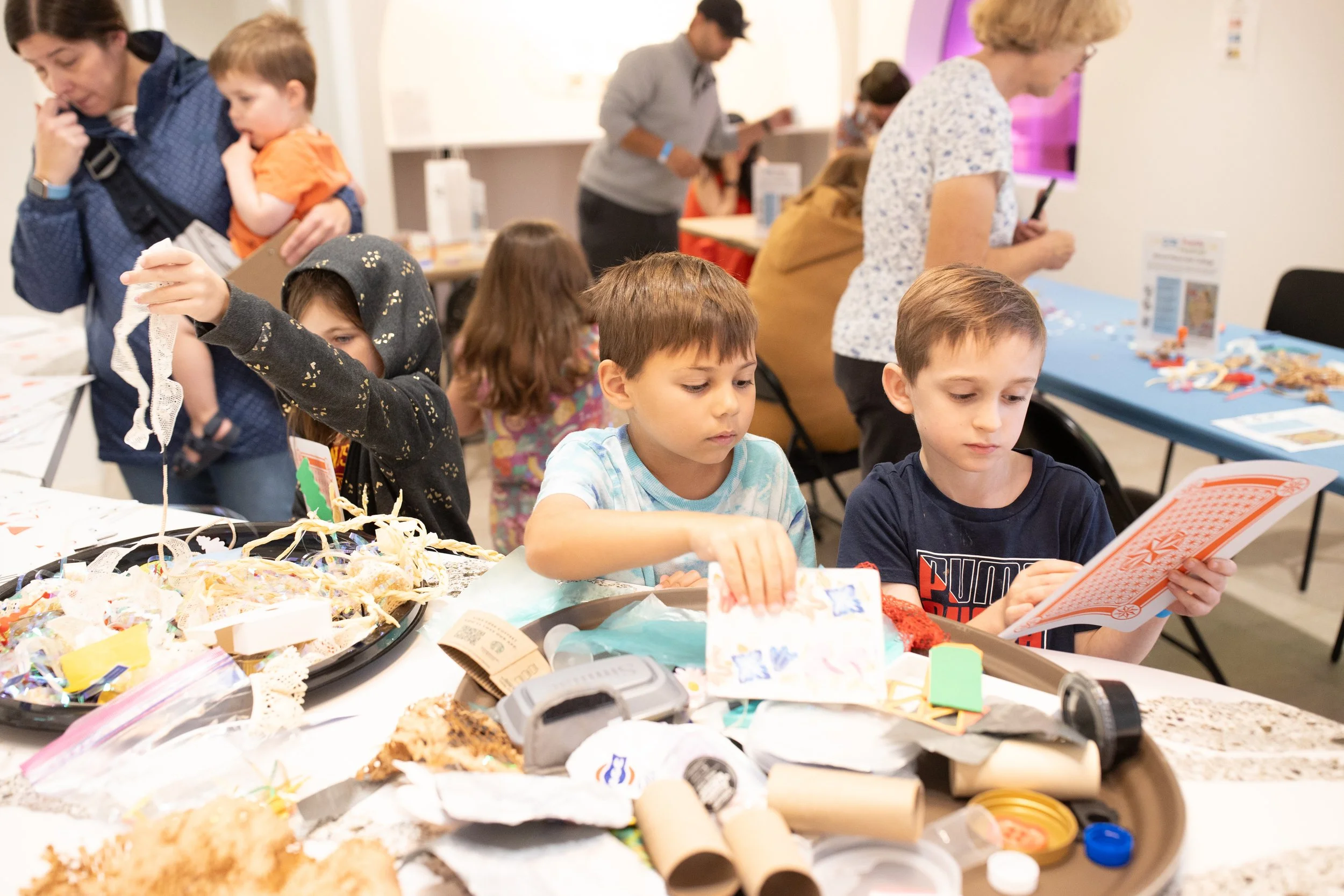 Children sorting through piles of mixed collage materials.