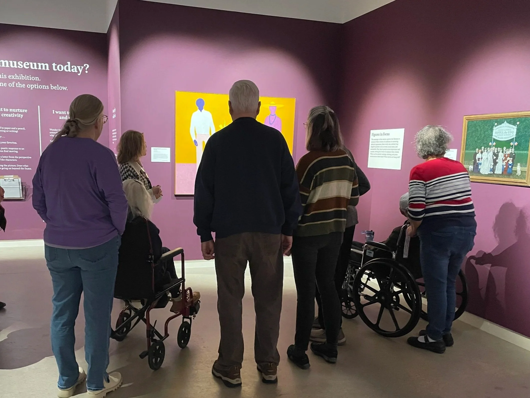 A group of older adults gather around a painting in the museum gallery.
