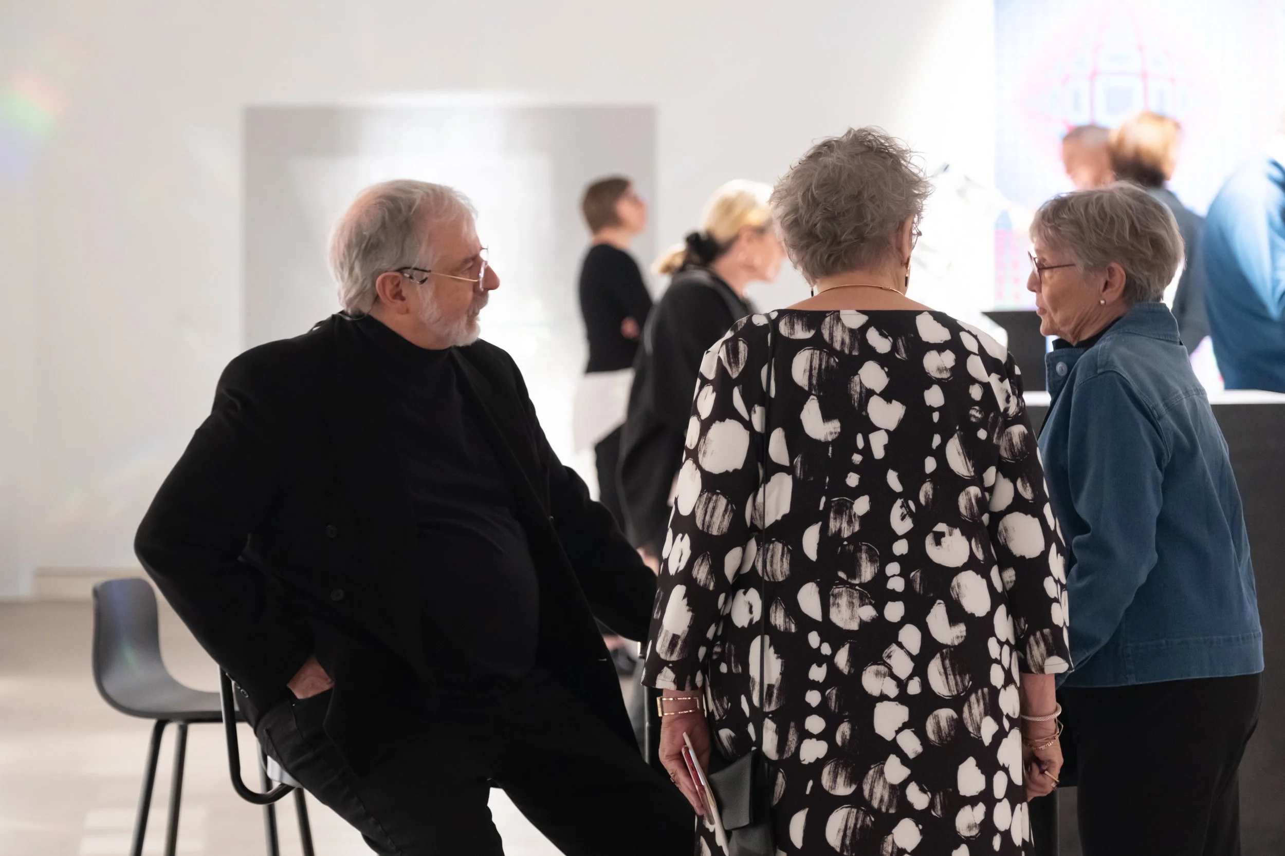 Two people converse with the artist Jon Kuhn.