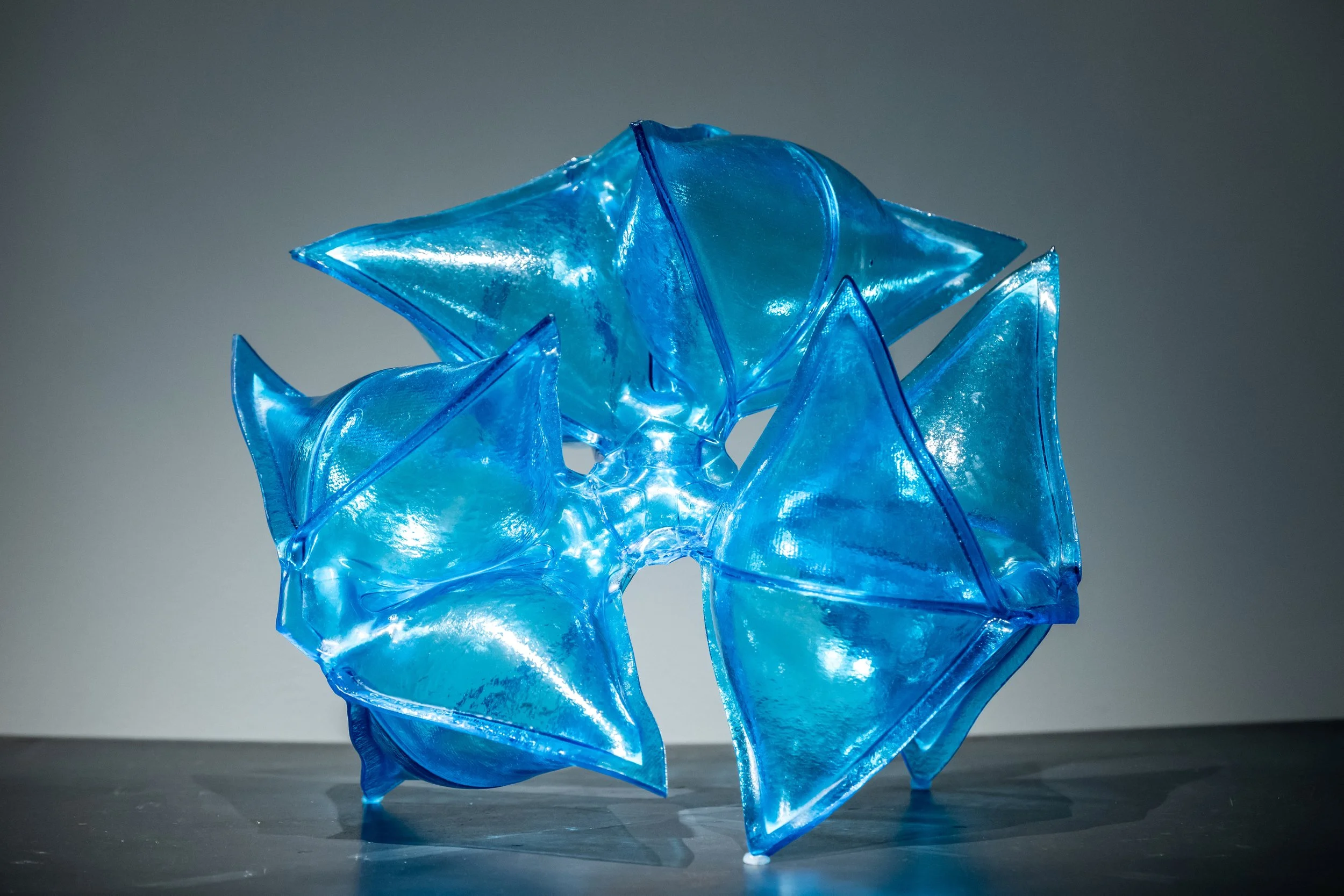 A blue glass sculpture with inflated angular pockets.