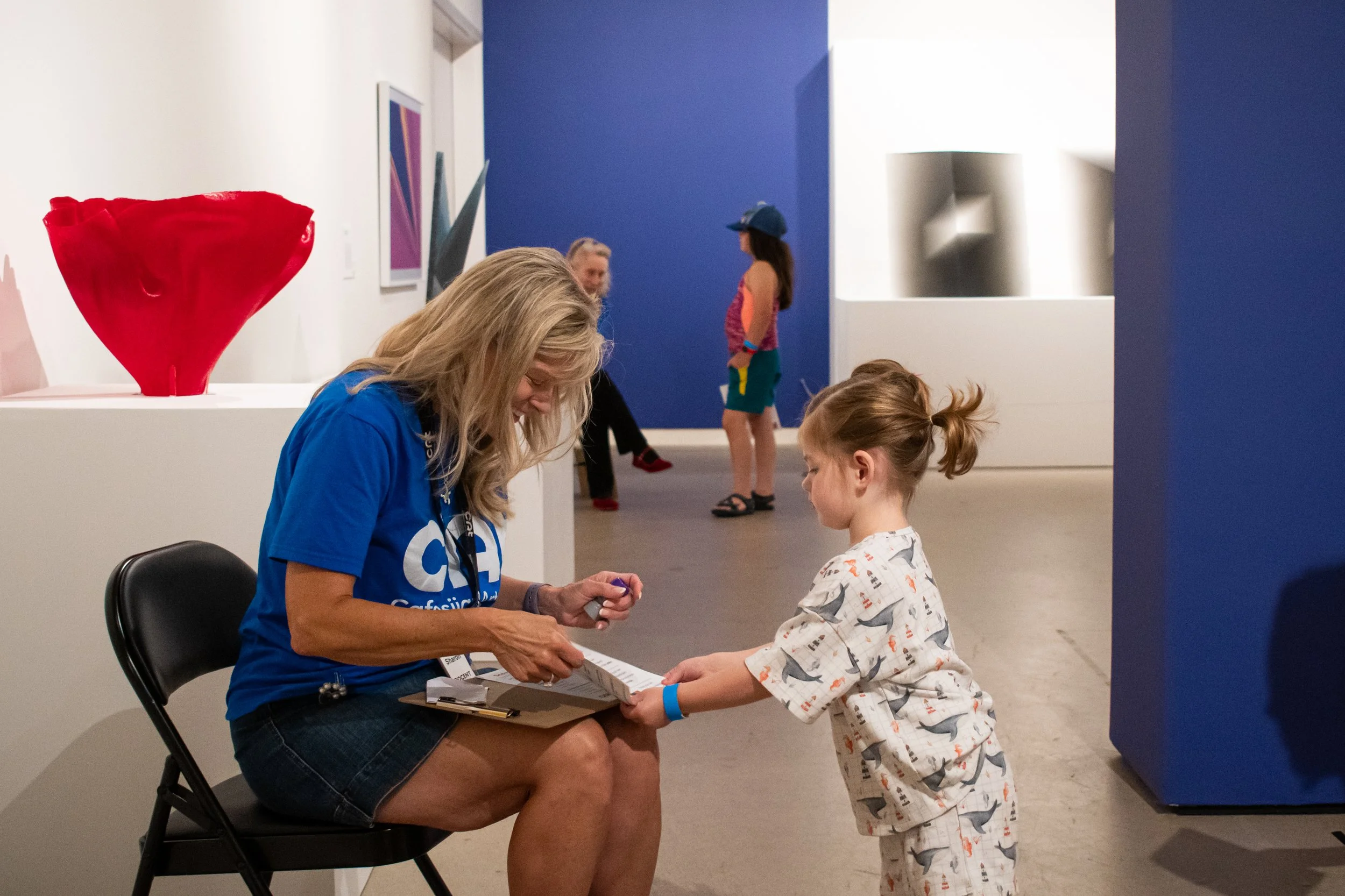A volunteer stamps a child's passport in the gallery. 