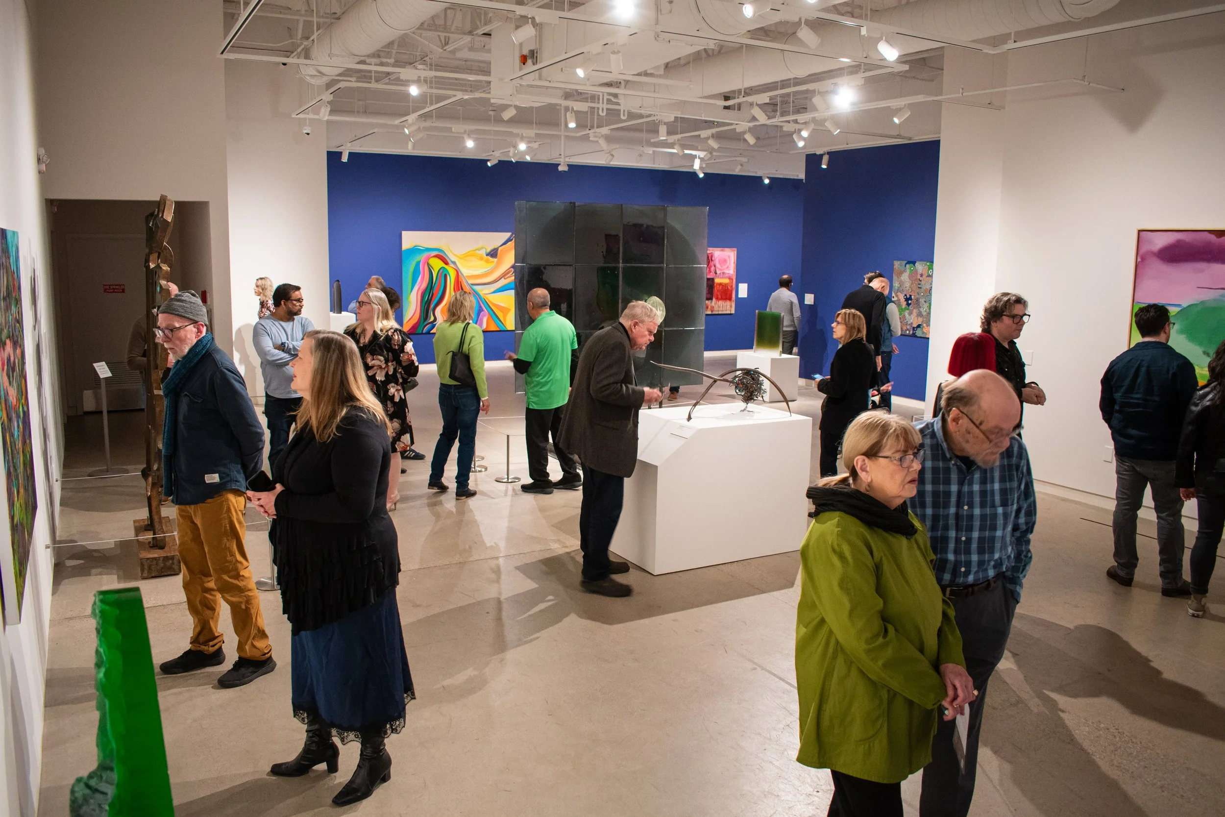 Guests at an opening celebration studying the exhibition.