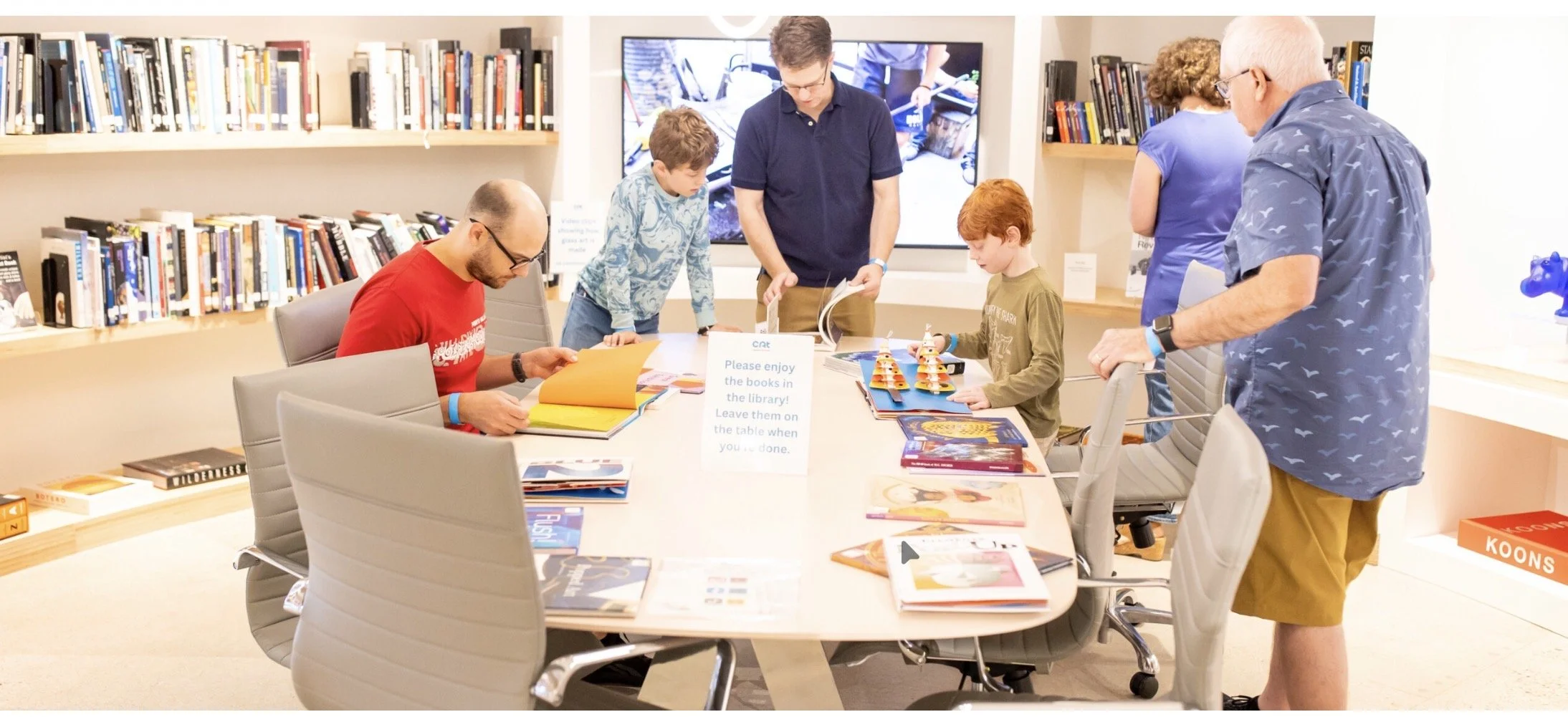 A multi-generational family studies books in the museum library.