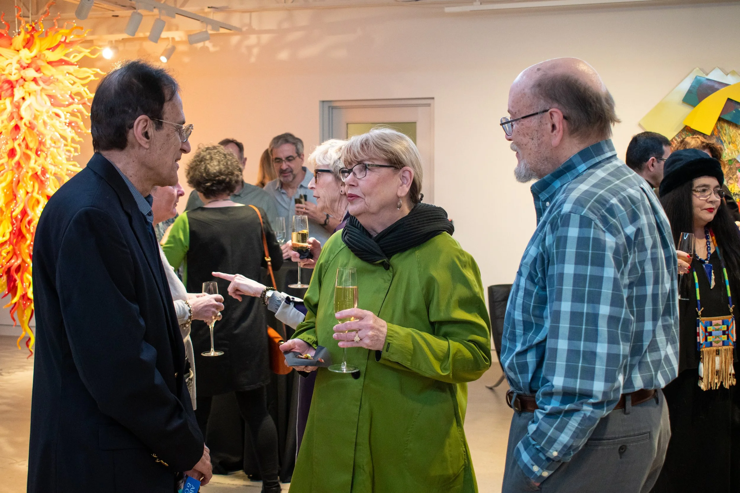 People having a conversation in the museum lobby while holding champagne.