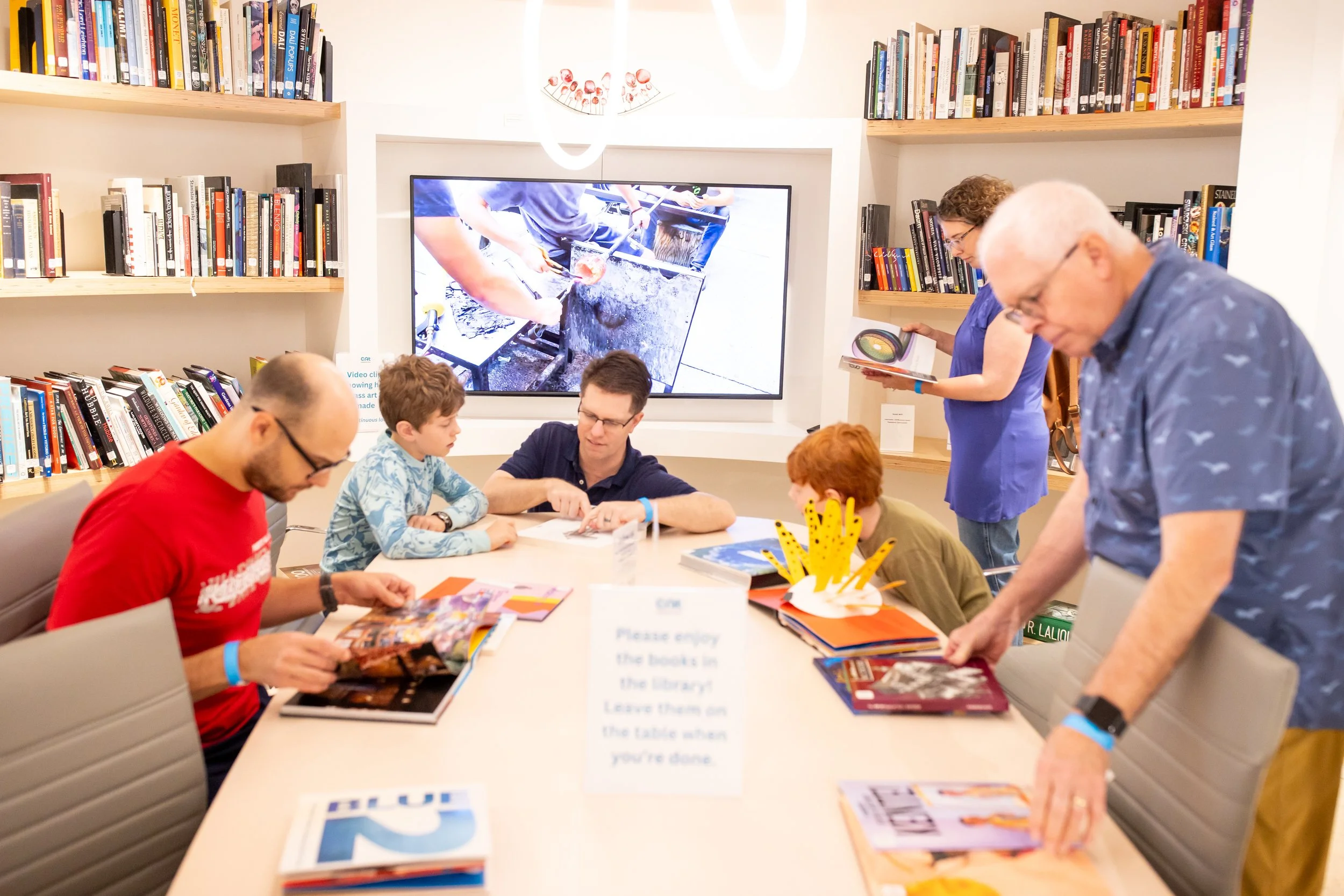 A multi-generational family studies books in the museum library.