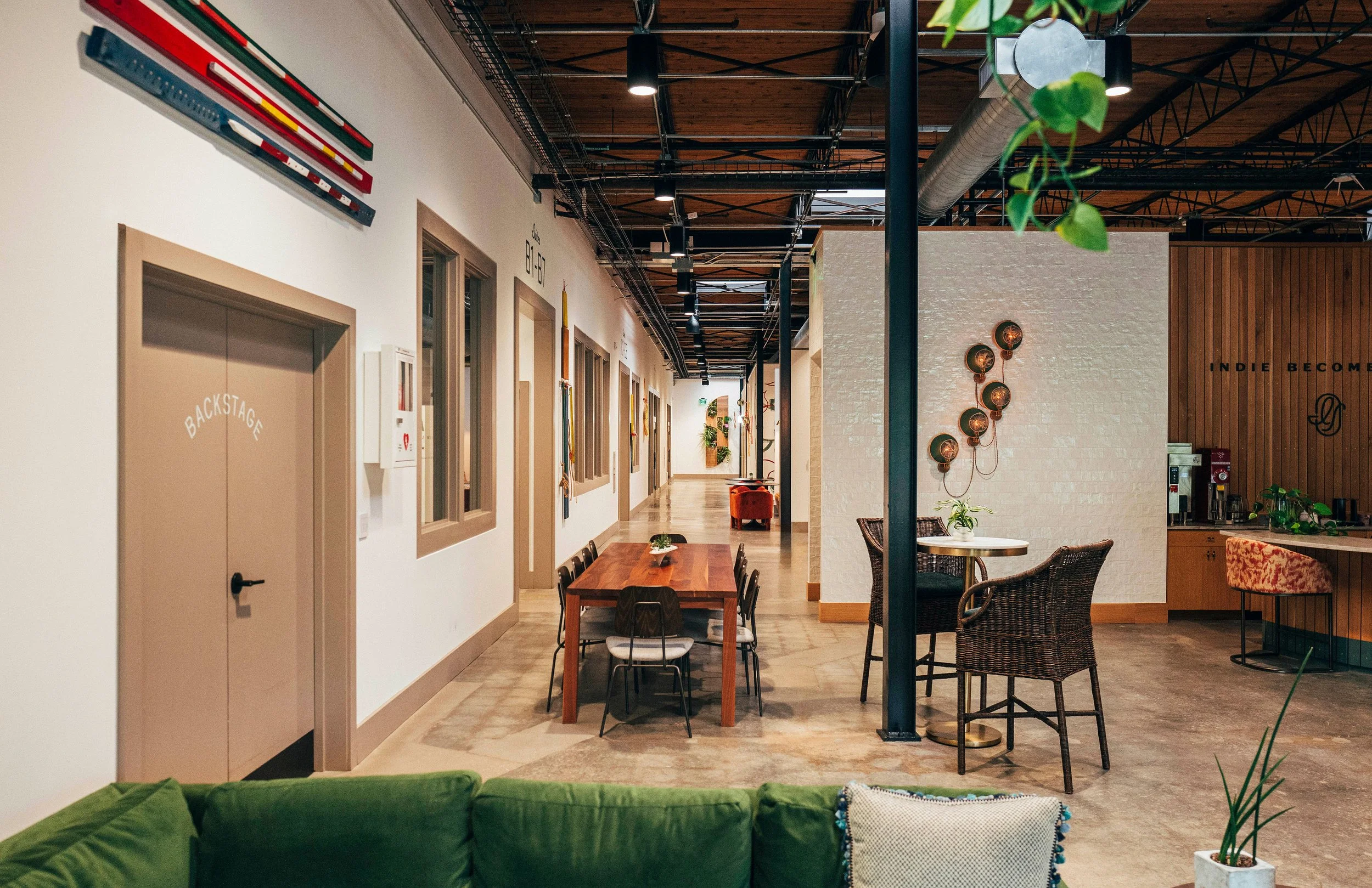 Interior of a modern office or co-working space with a seating area, wooden ceiling, and decorative wall art.