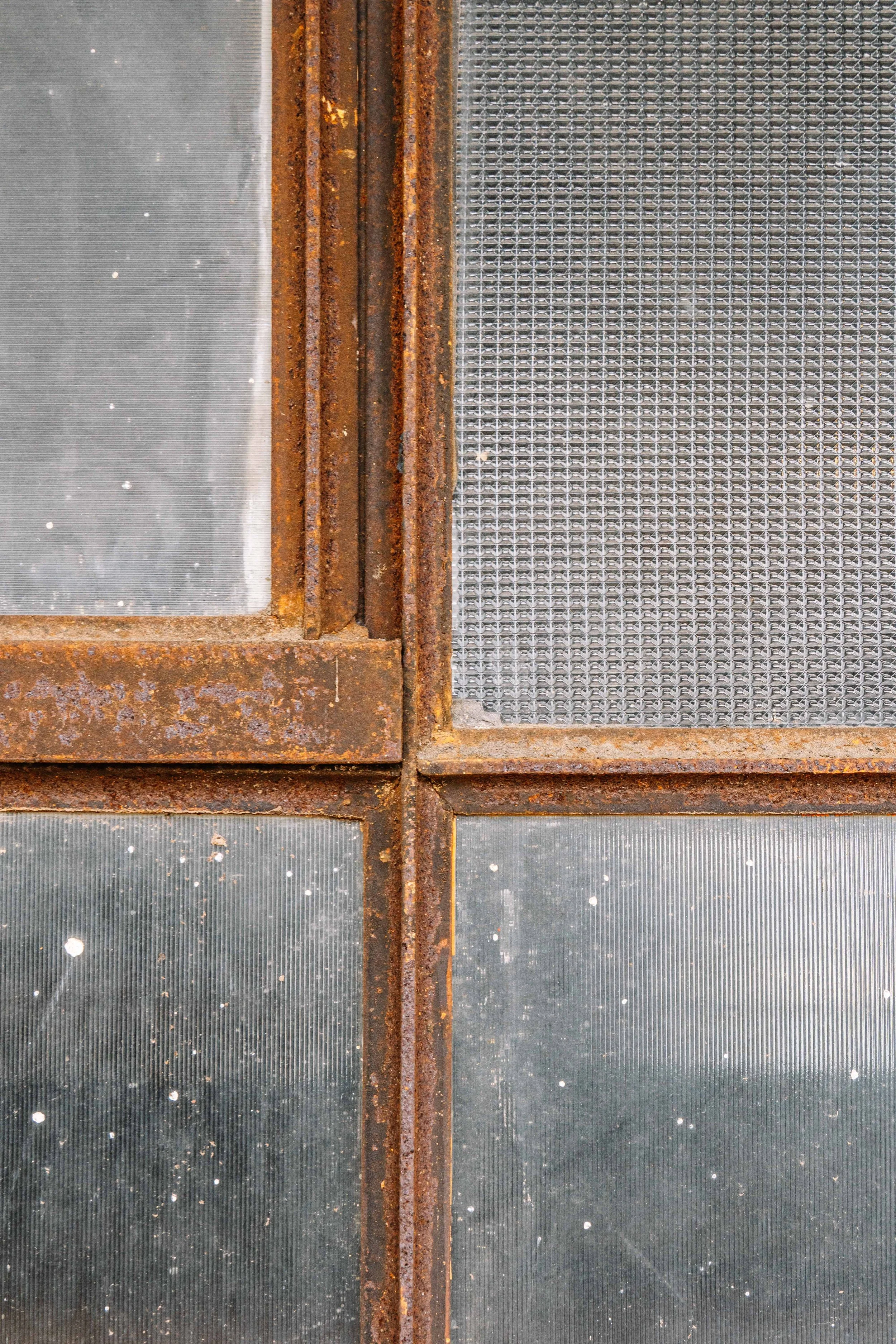 Close-up of rusted metal frames and wire mesh panels, with some dirt and dust particles on the surfaces.
