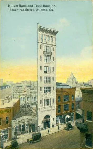 A drawing of the Hillyer Bank and Trust Building on Peachtree Street in Atlanta, Georgia, showing a tall, narrow, multi-story historic building with several windows, surrounded by other older buildings and street-level stores with vintage cars parked along the street.