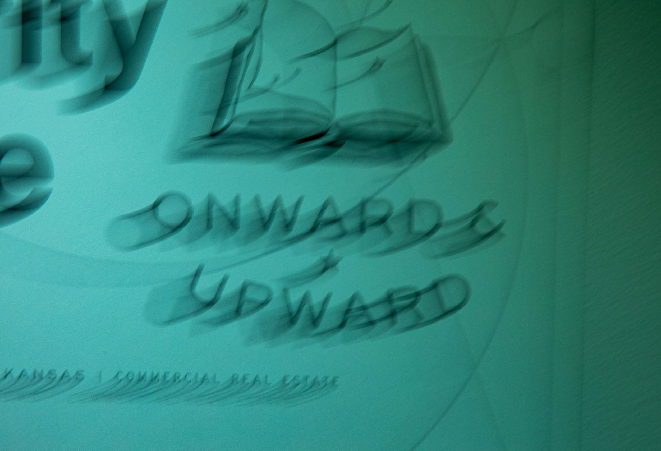 Close-up of a teal-colored surface with black cursive writing and a black line drawing of a butterfly.